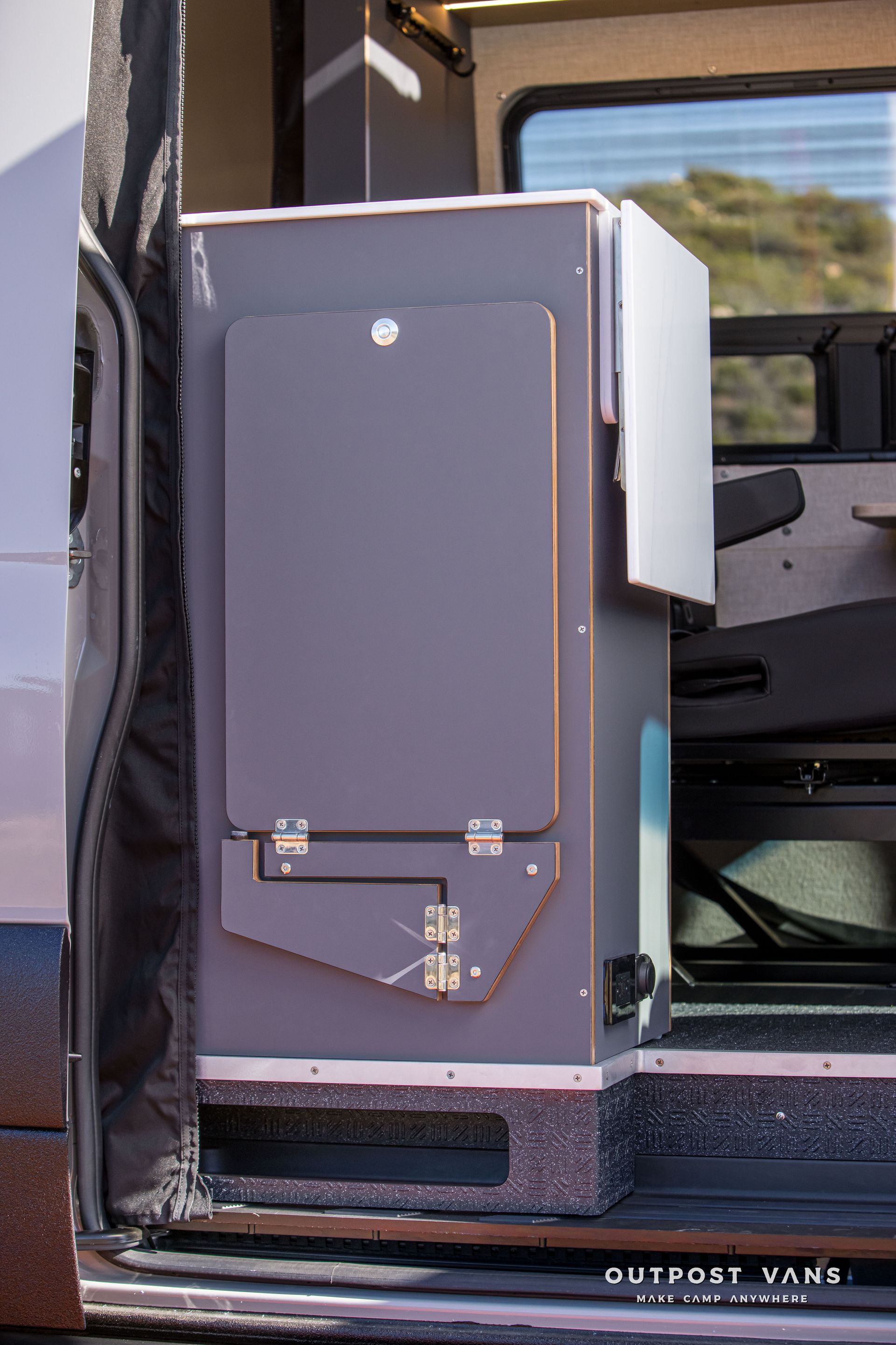 Gray camper van cabinet with a folding table, seen from the side with the door open.