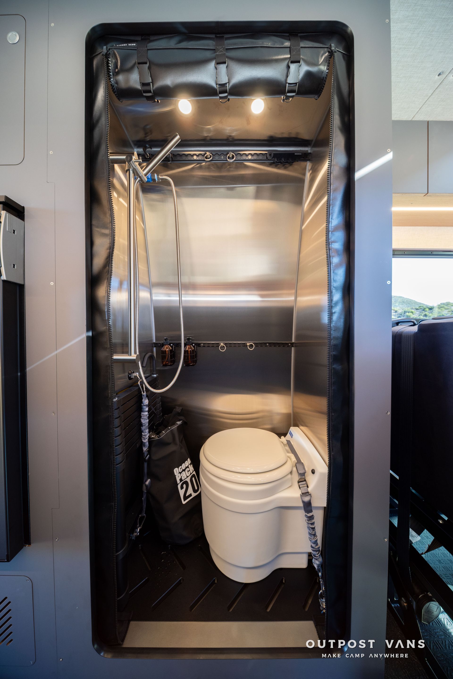Small, stainless steel shower and composting toilet in a van. Black trim and floor.