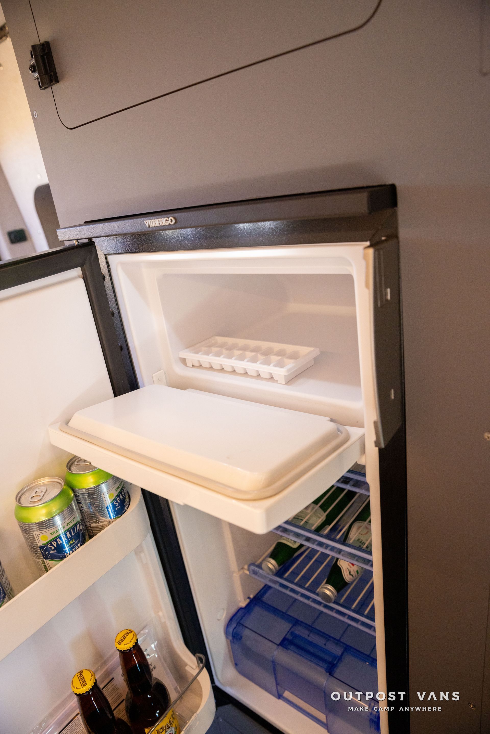 Open mini fridge with beverages and ice tray.