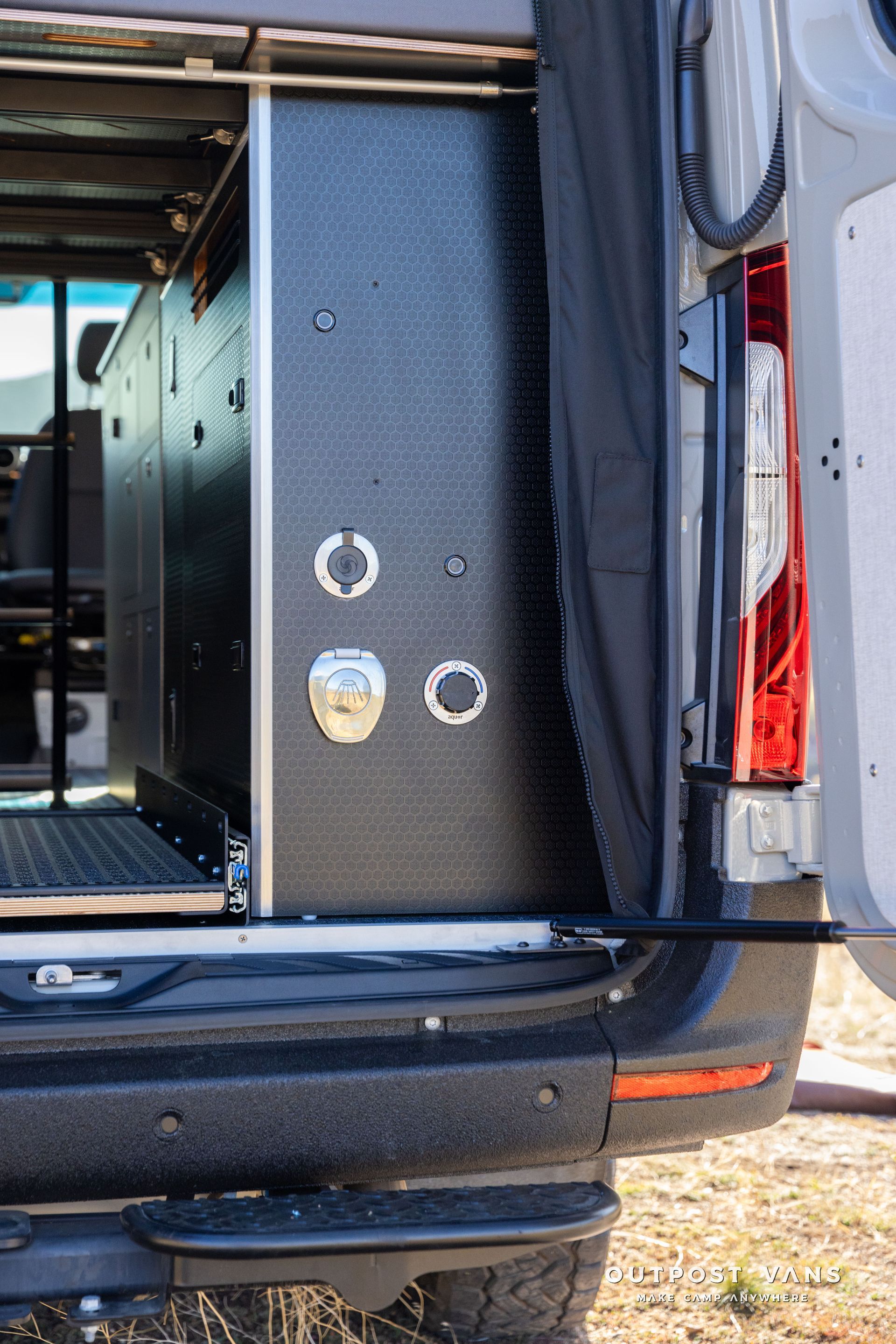 Black campervan cabinetry with water access points, next to the rear taillight.