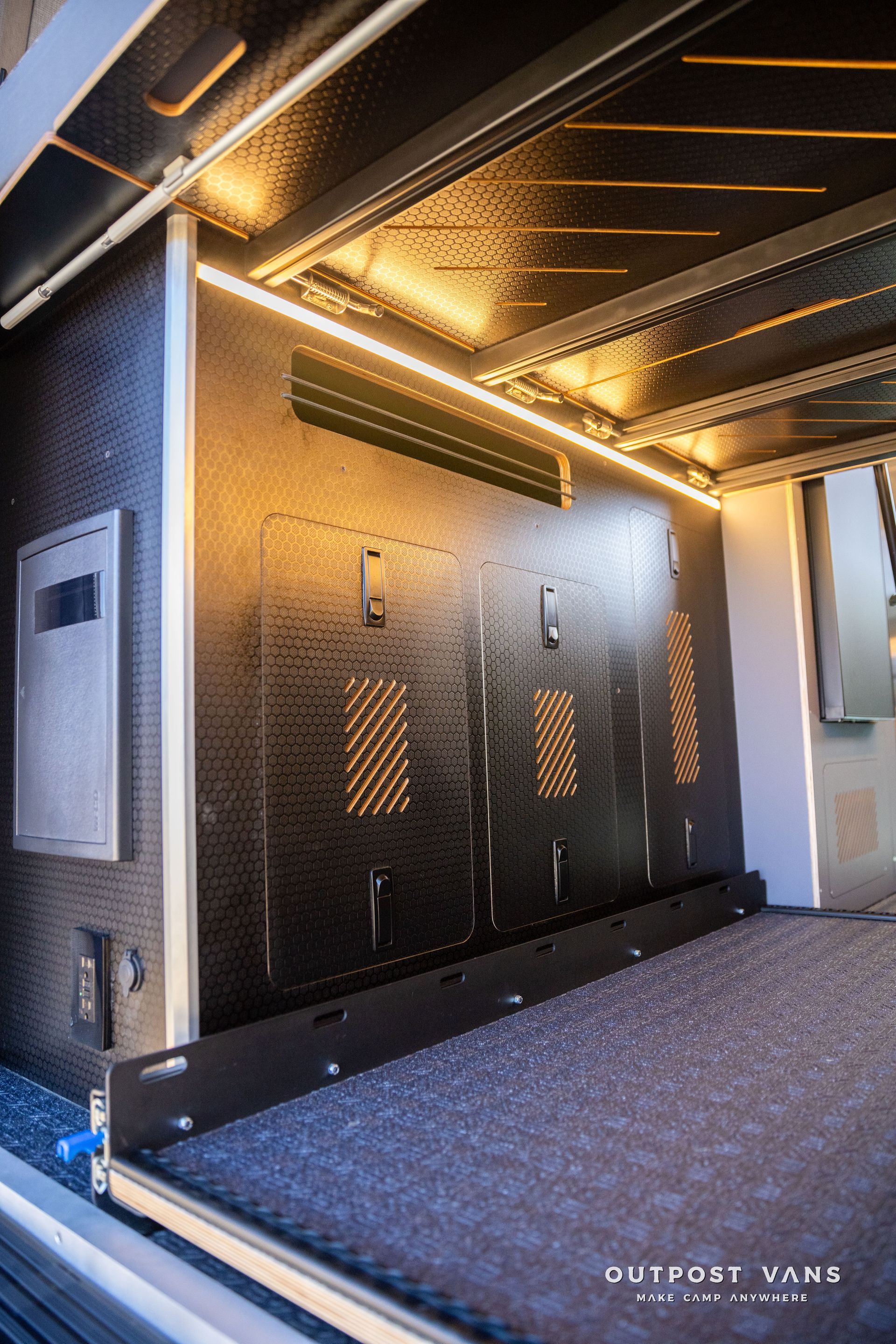 Interior of a vehicle storage system with LED lighting, black panels, and a sliding drawer.