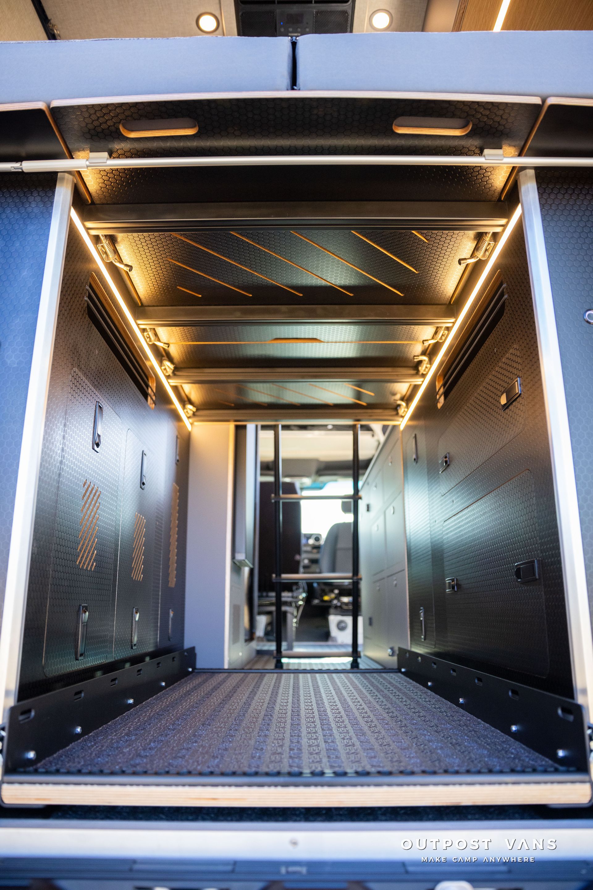 Interior of a vehicle with a cargo area, showing a textured floor and walls, illuminated with warm lighting.