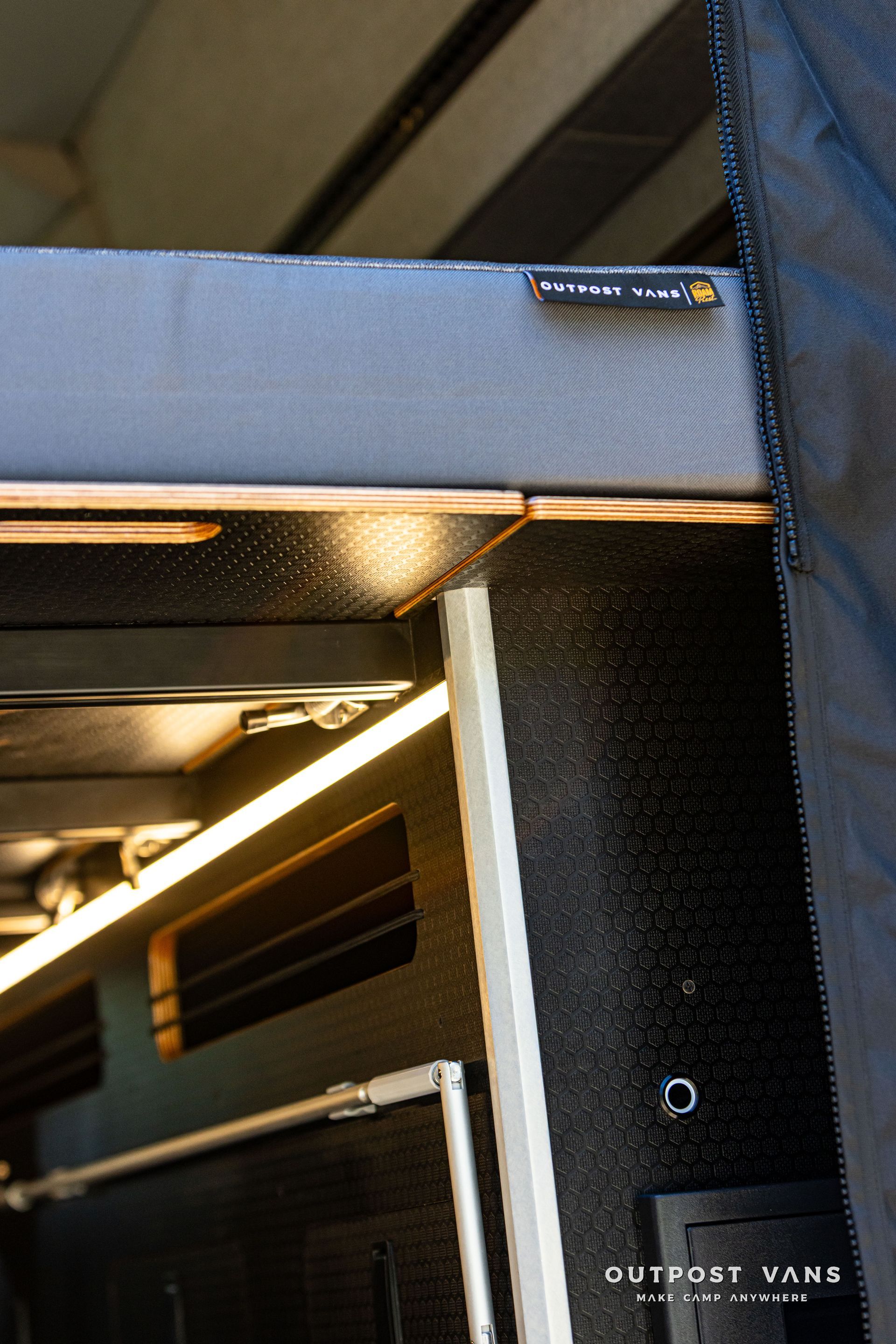 Close-up of a blue structure with a metal hinge and black fabric panel under warm lighting