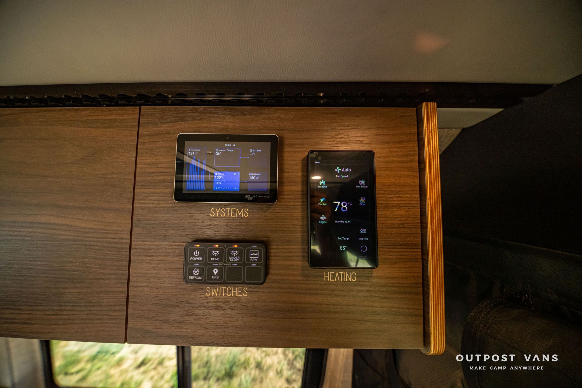 Wood panel wall with two digital control panels and a thermostat in an RV interior
