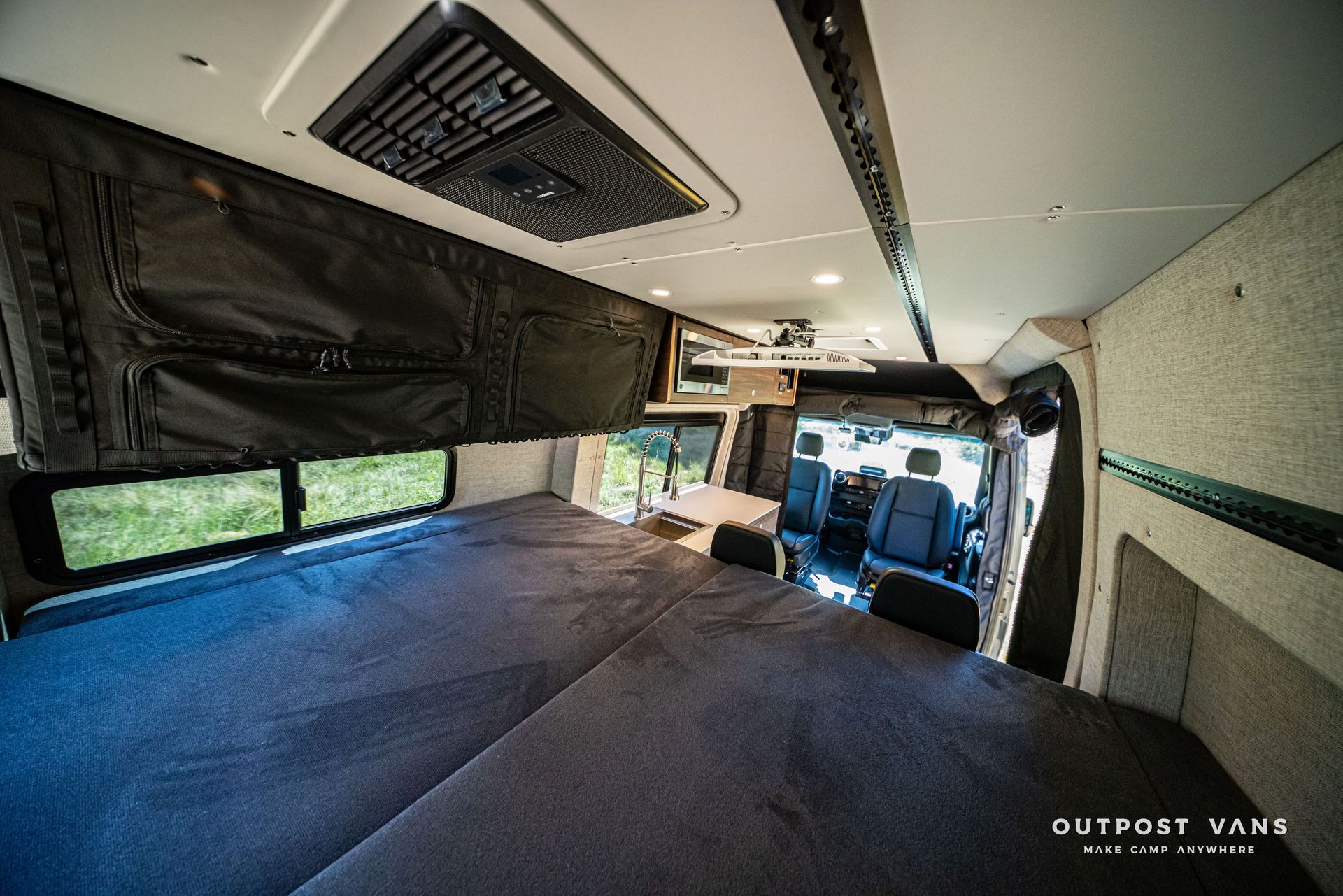 Van with converted camper interior: bed platform, cabinets, windows, and ceiling vents.