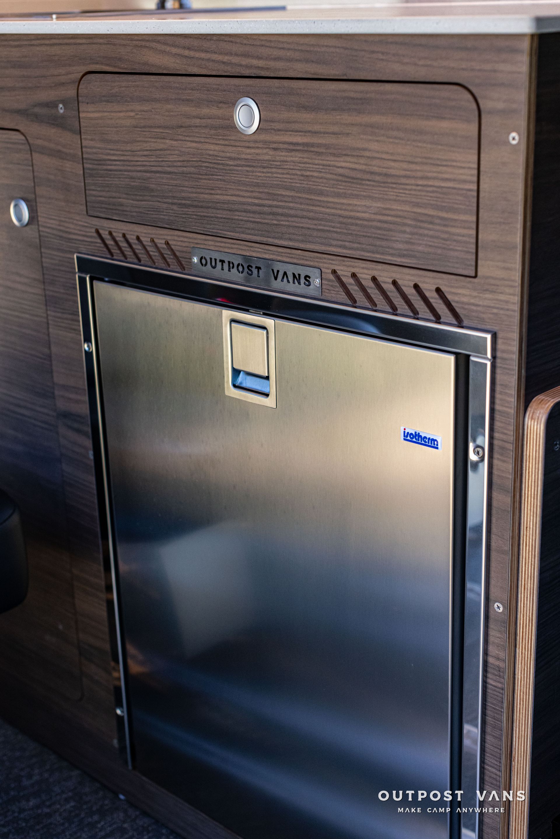 Wood-paneled mini fridge built into a cabinet, with a silver door and black trim.