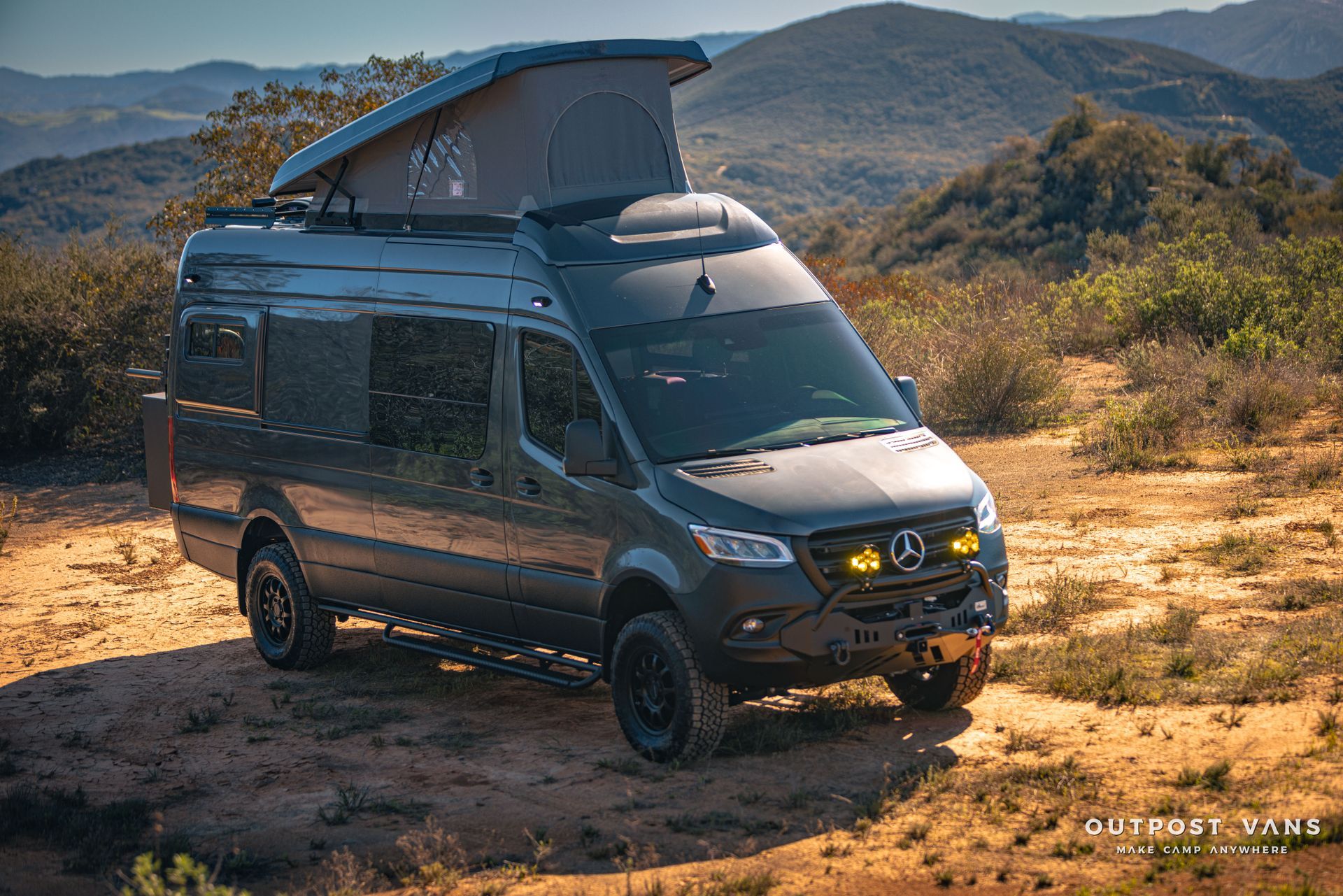 a van with a pop up roof is parked in a dirt field .