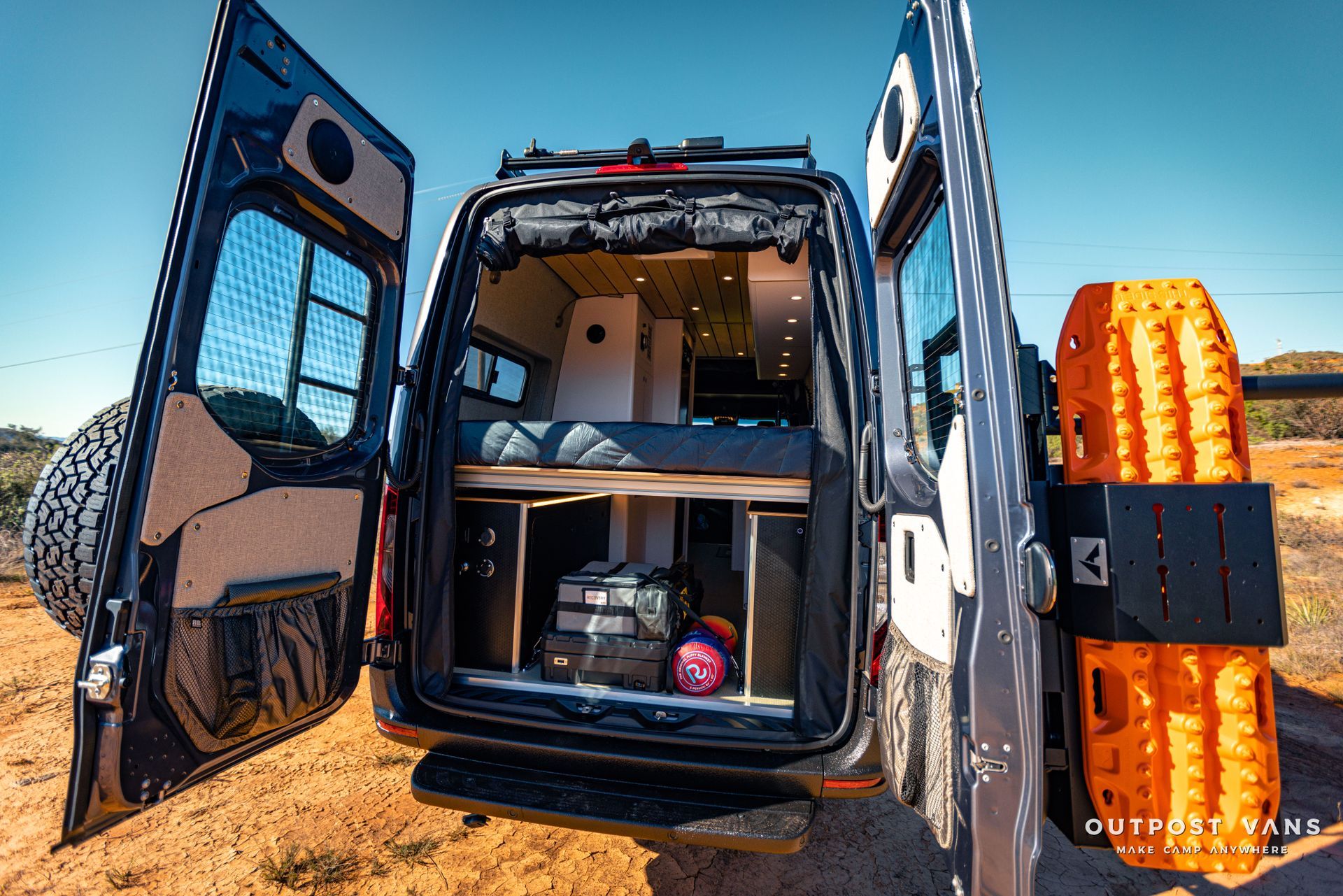 a van with its doors open is parked in the desert .