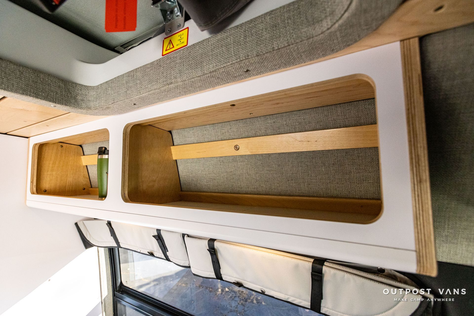 a shelf in a van with a bottle of water on it .