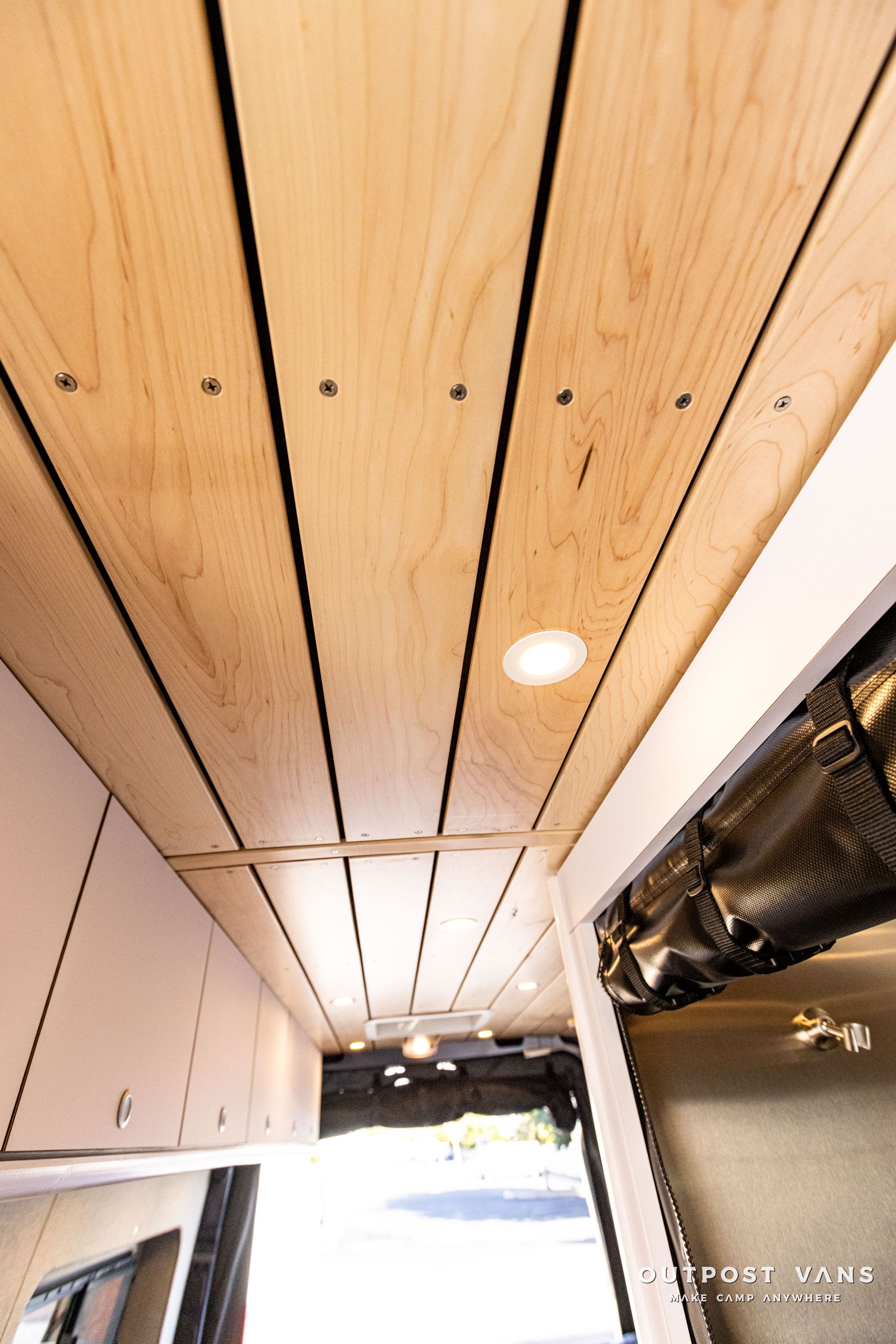 the ceiling of a van is made of wood and has a light on it .