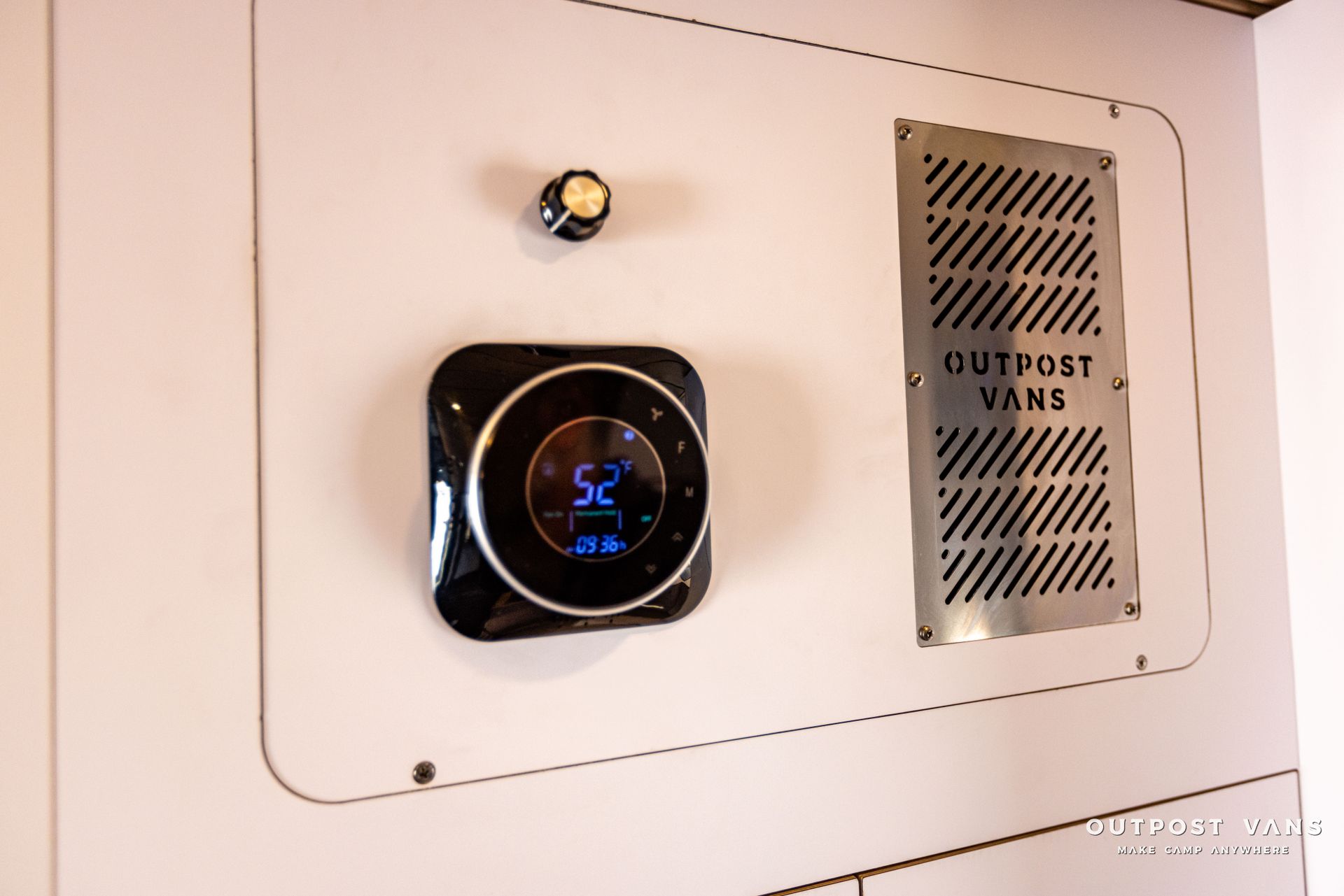 a thermostat is hanging on a wall next to a sign that says outpost vans .