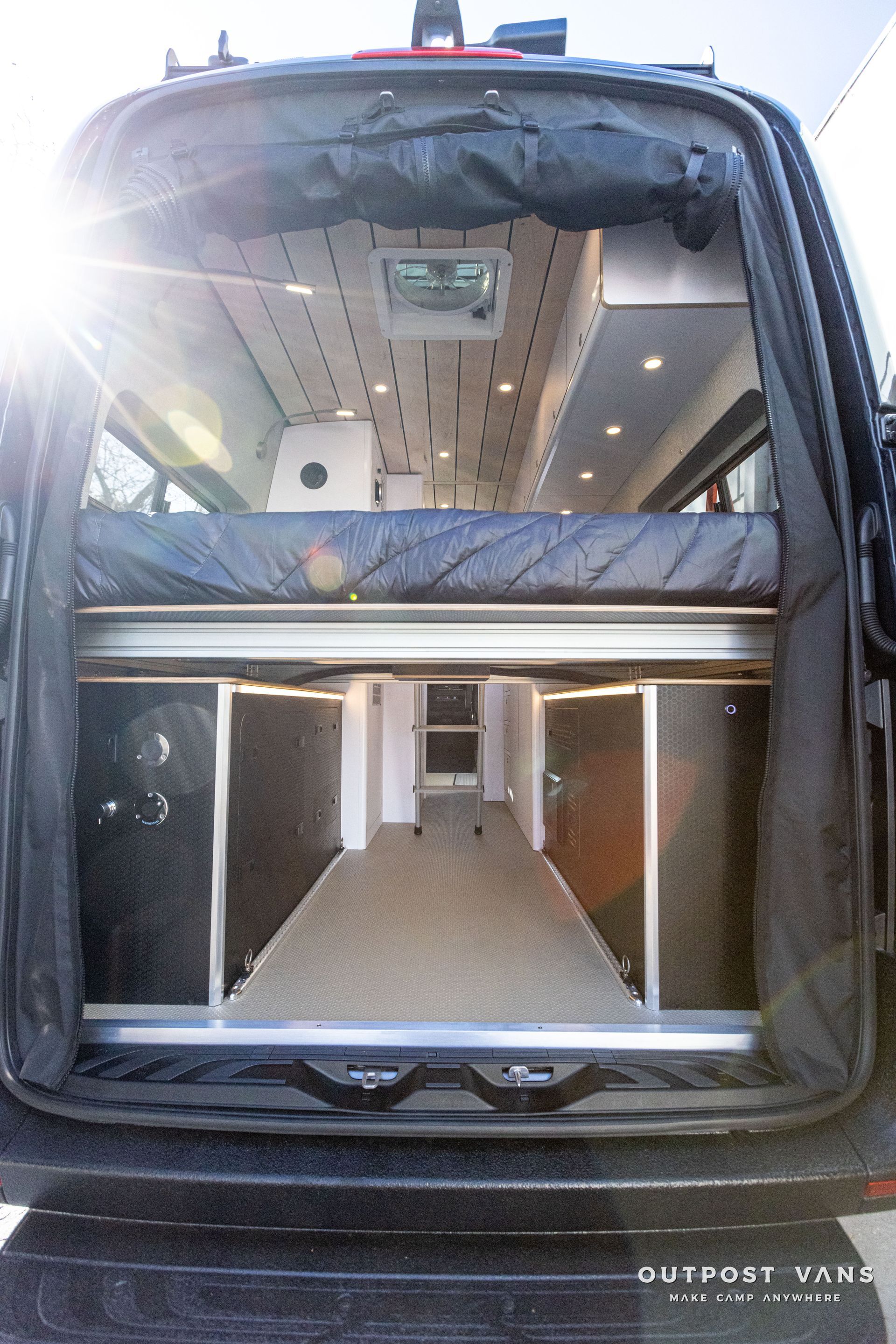 the back of a van with the door open and a bed in the back .