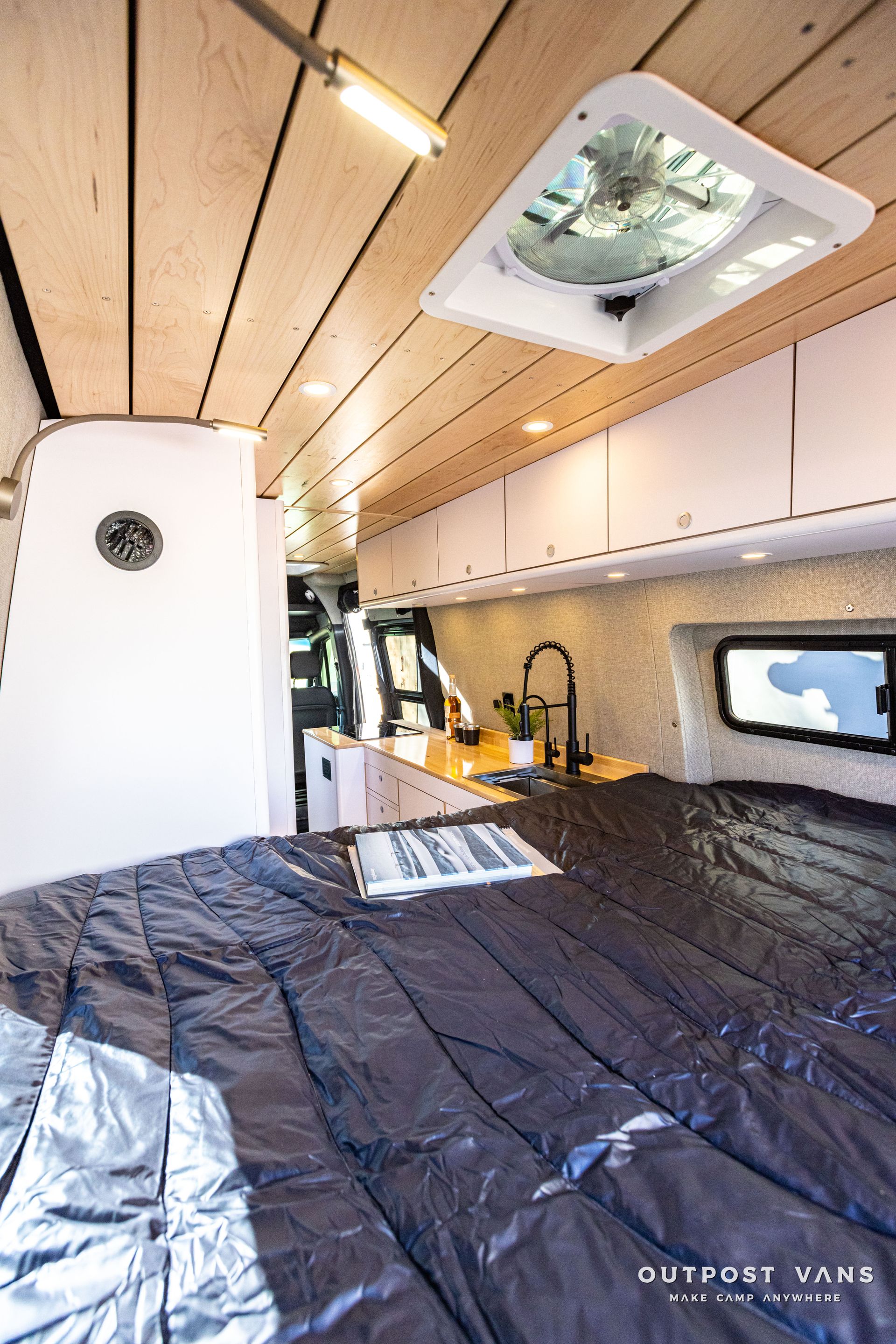 the inside of a van with a bed and a fan on the ceiling .