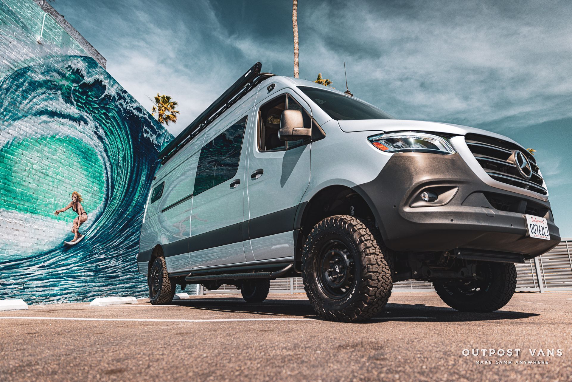 a van is parked in a parking lot in front of a wave .