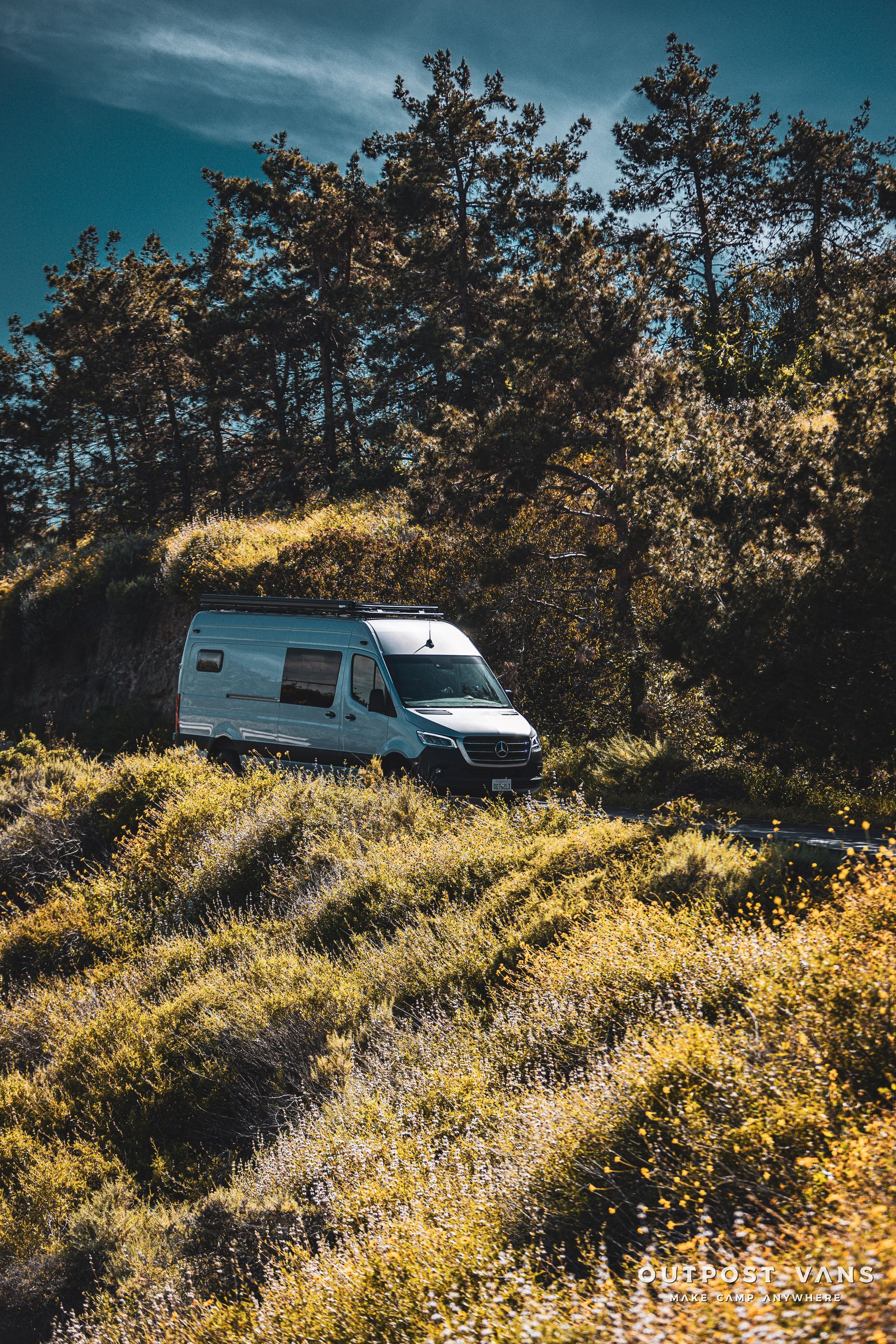 a white van is driving through a field of grass and trees .