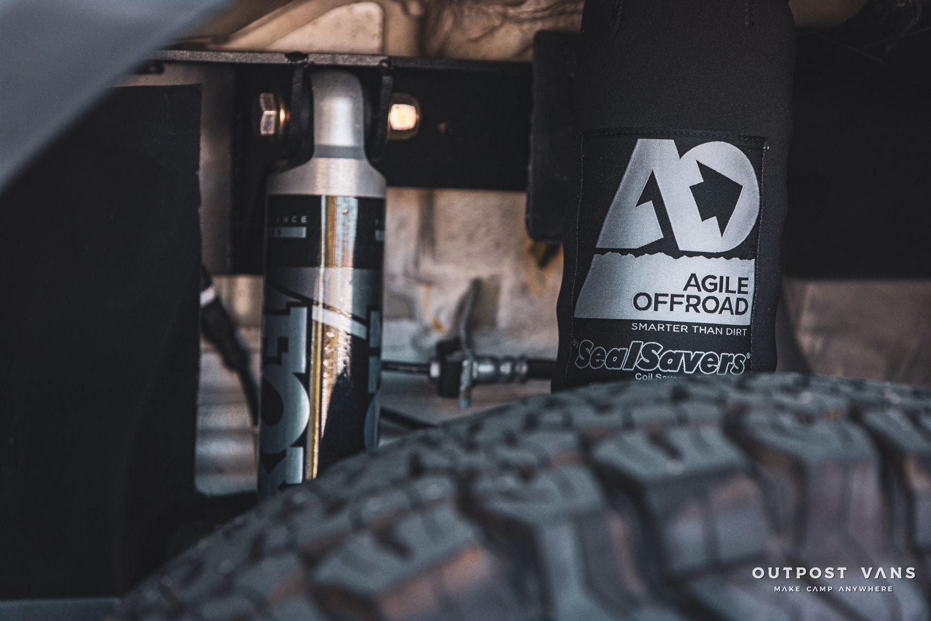 a close up of a suspension system on a truck with a tire in the background .