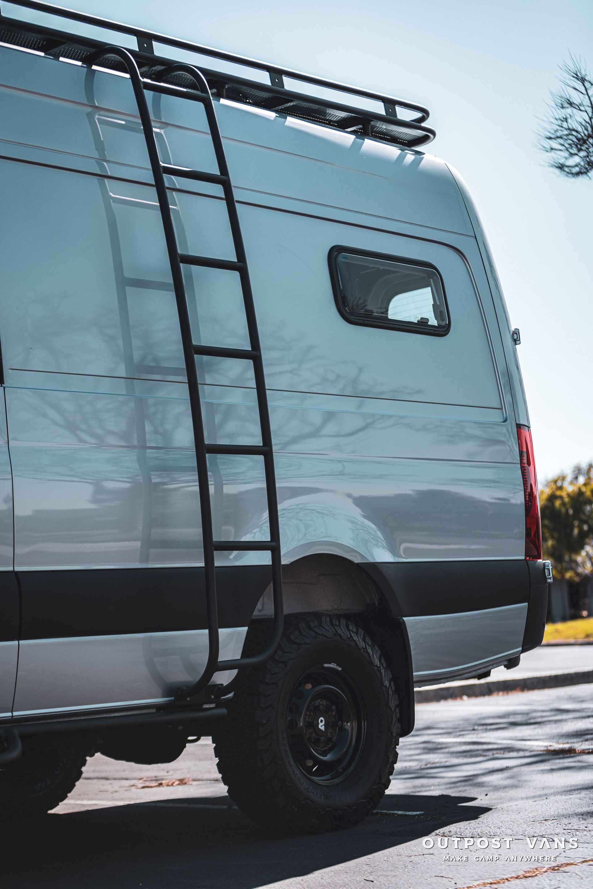 a white van with a ladder on the side is parked on the side of the road .