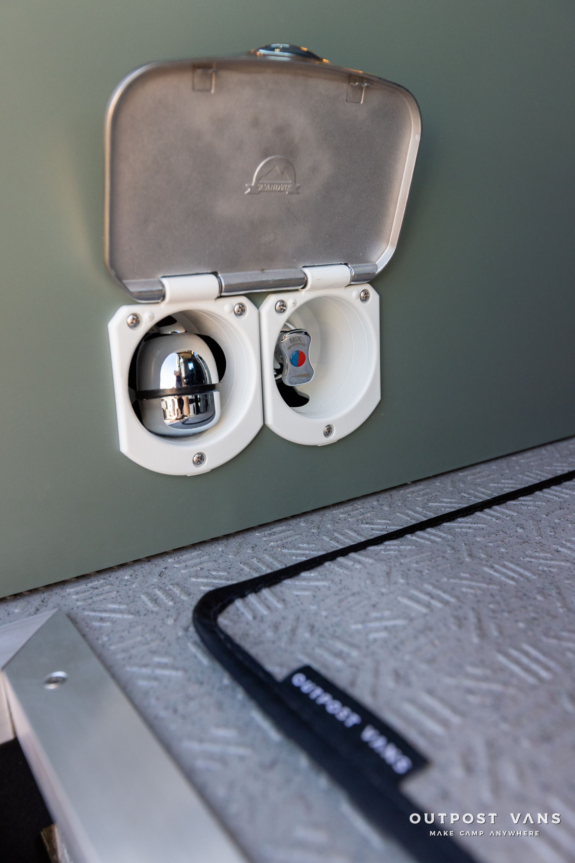 a close up of a stainless steel electrical outlet on a wall .