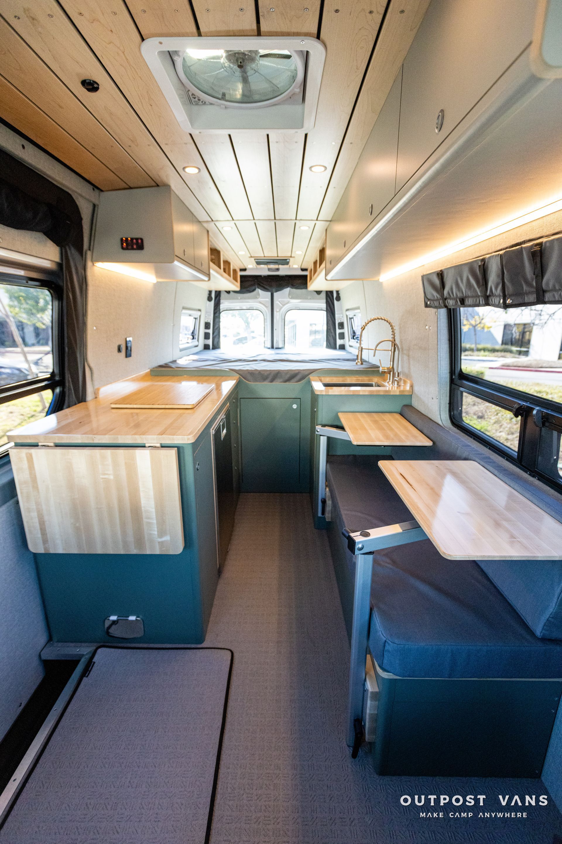 the inside of a camper van with tables and a sink .