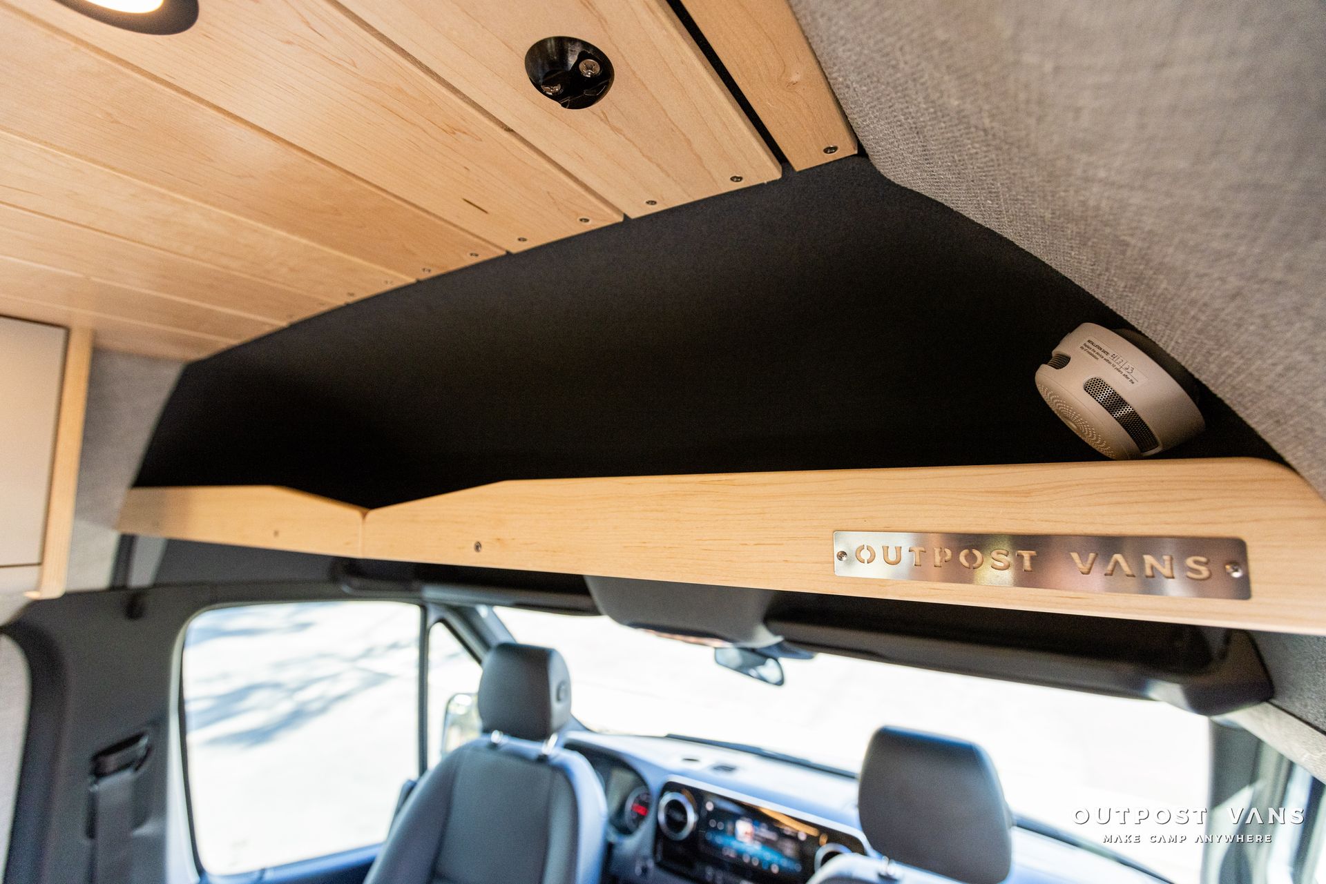 the ceiling of a van has a shelf and a fire alarm on it .