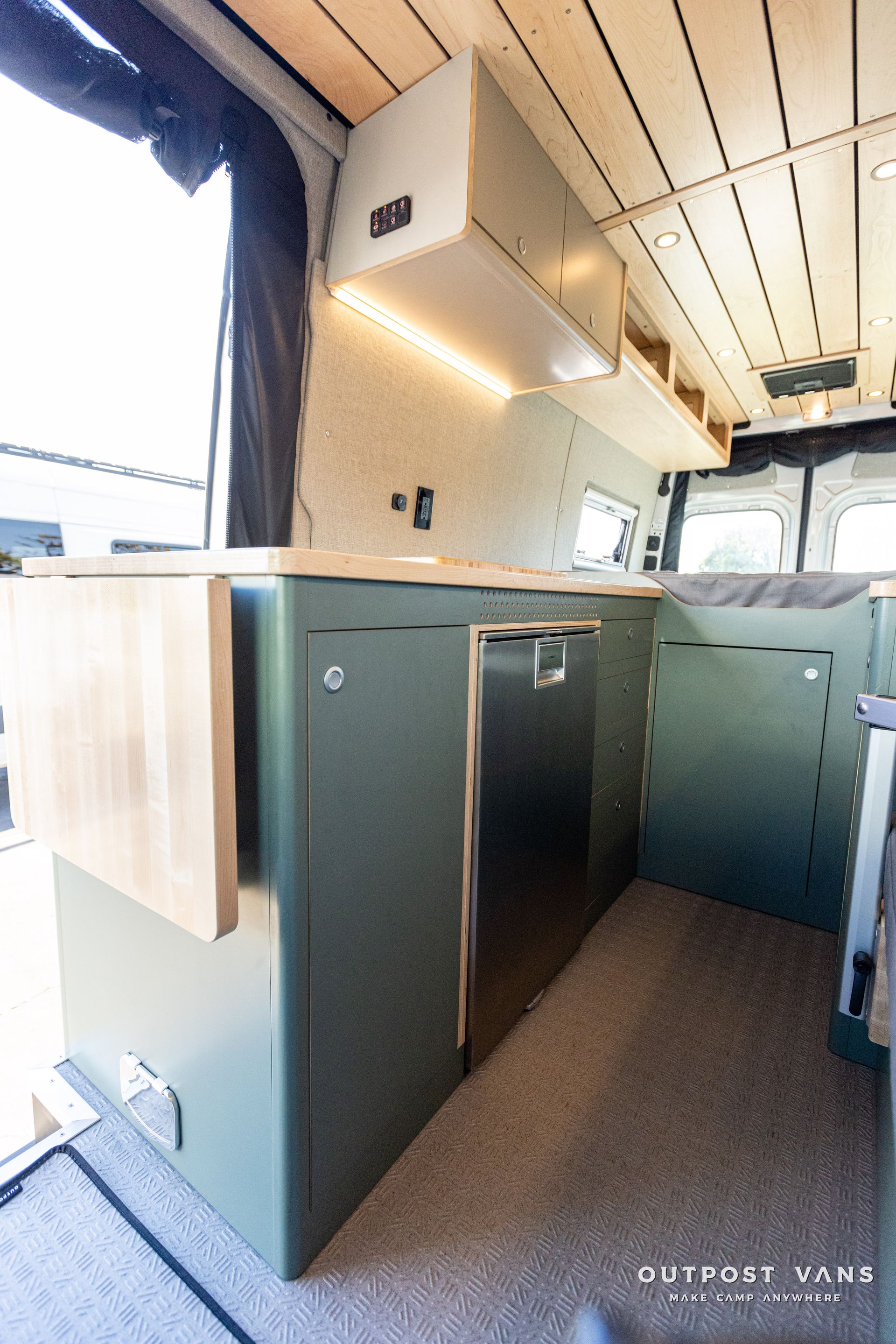 the inside of a camper van with green cabinets and a bed .
