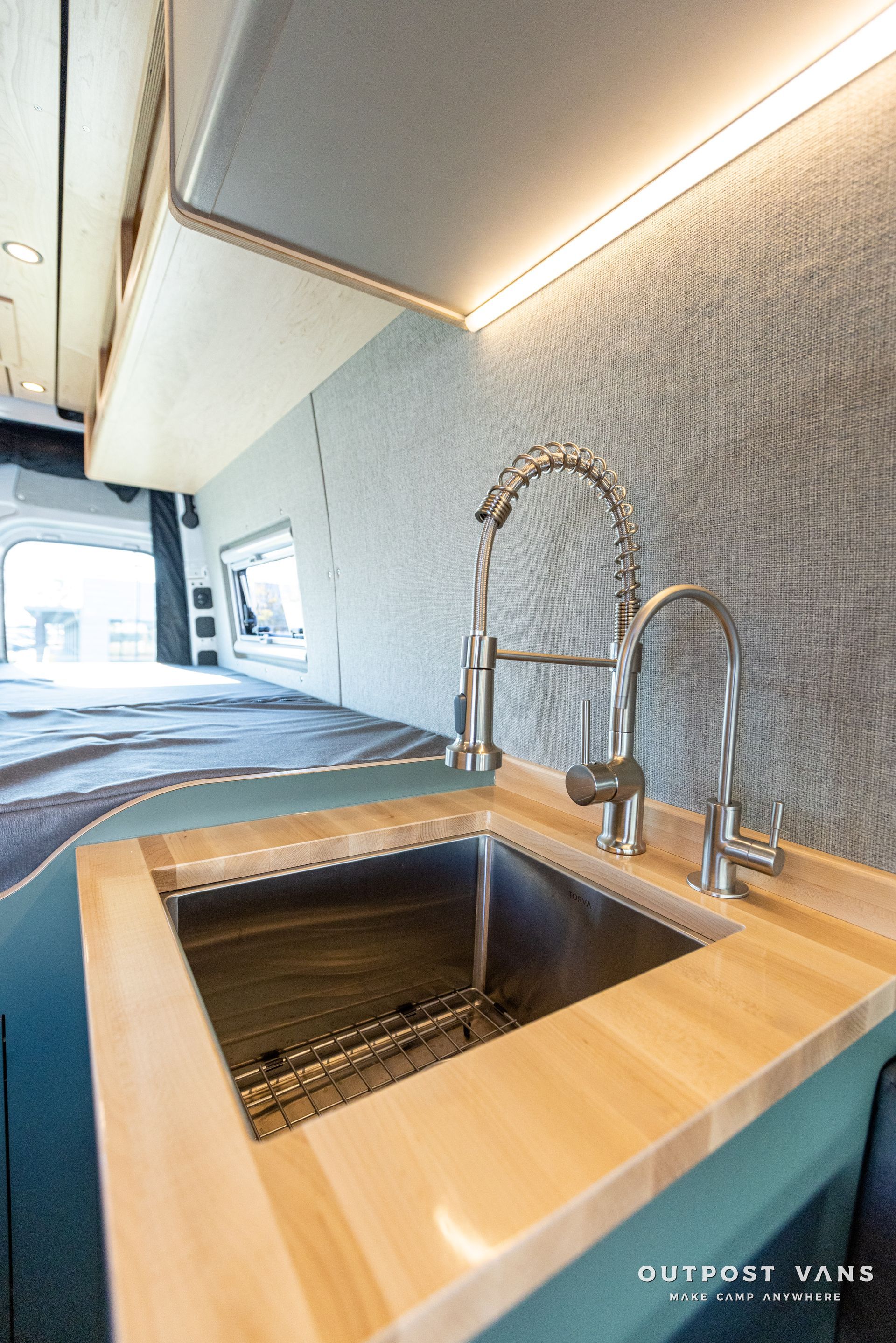 a kitchen sink with a faucet on a wooden counter top .