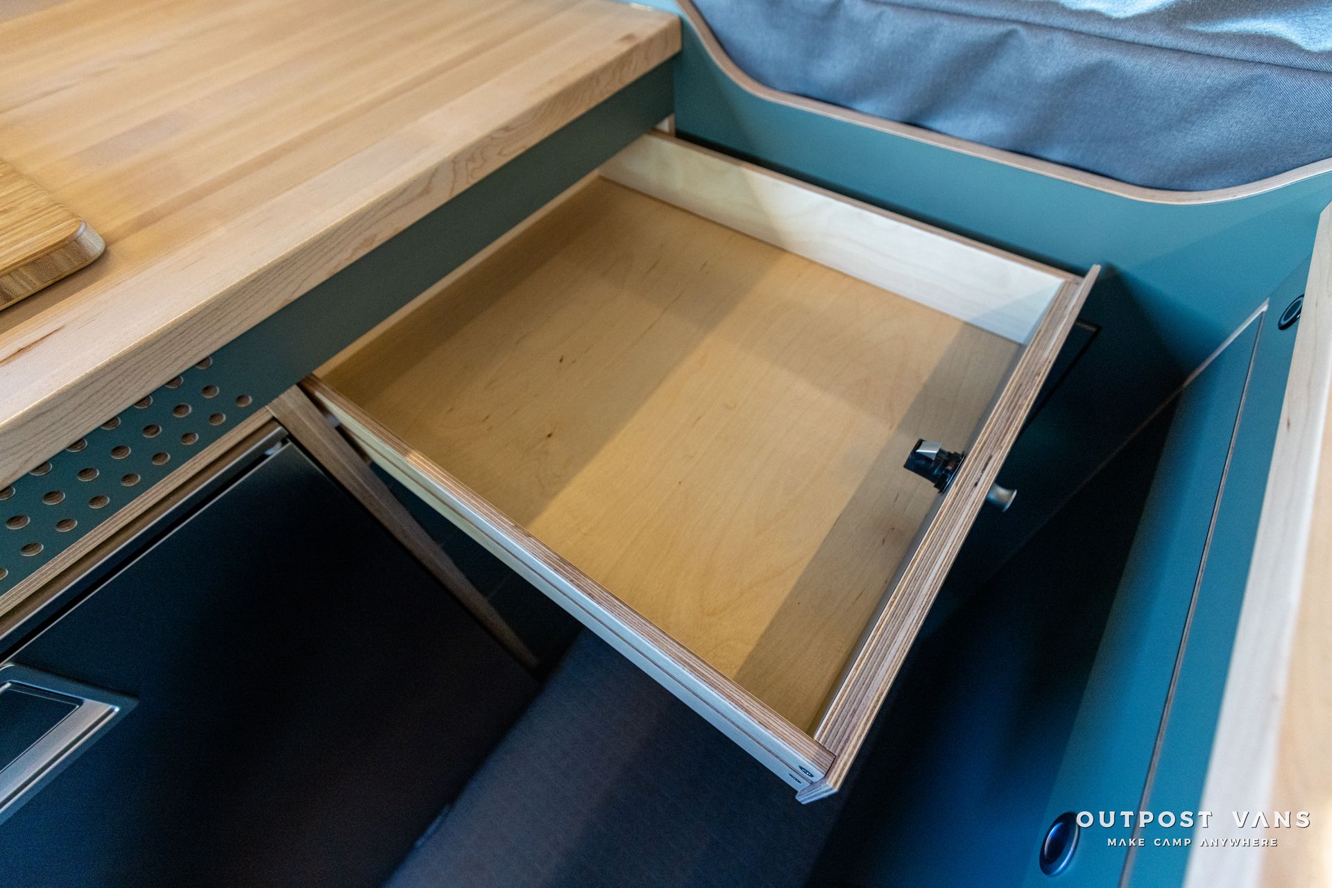 a wooden drawer is open in a camper van .