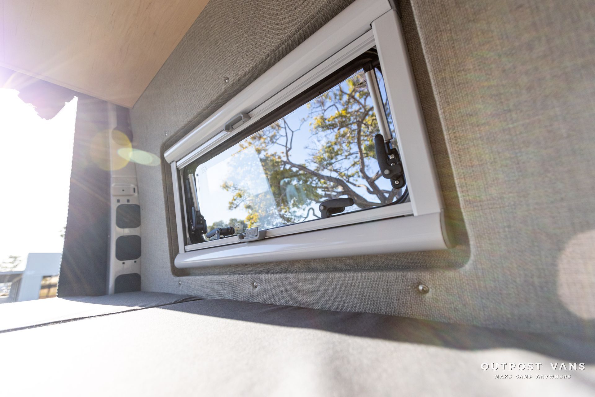 a window on the side of a building with a tree in the background .