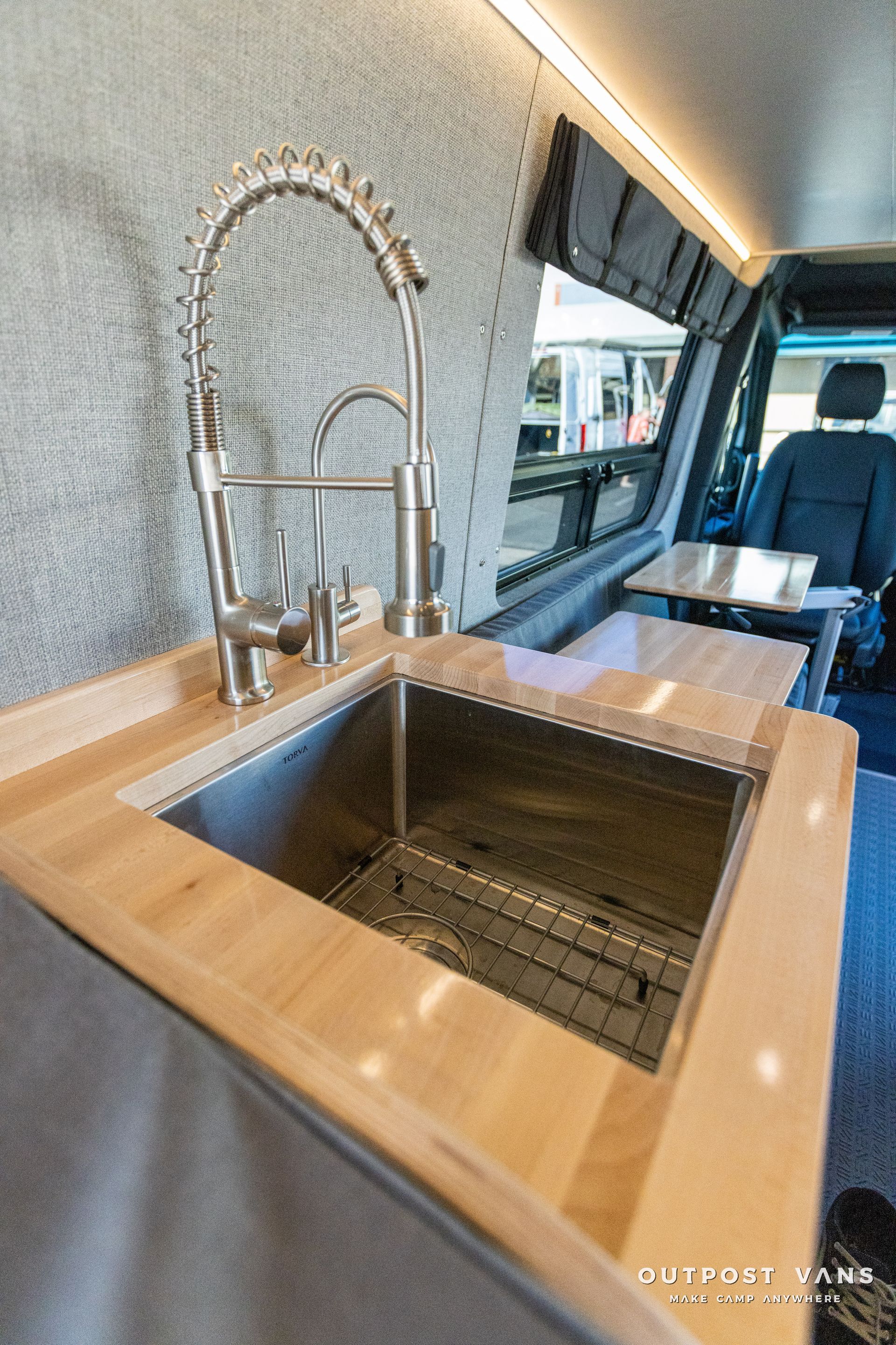 a stainless steel sink with a wooden counter top in a van .