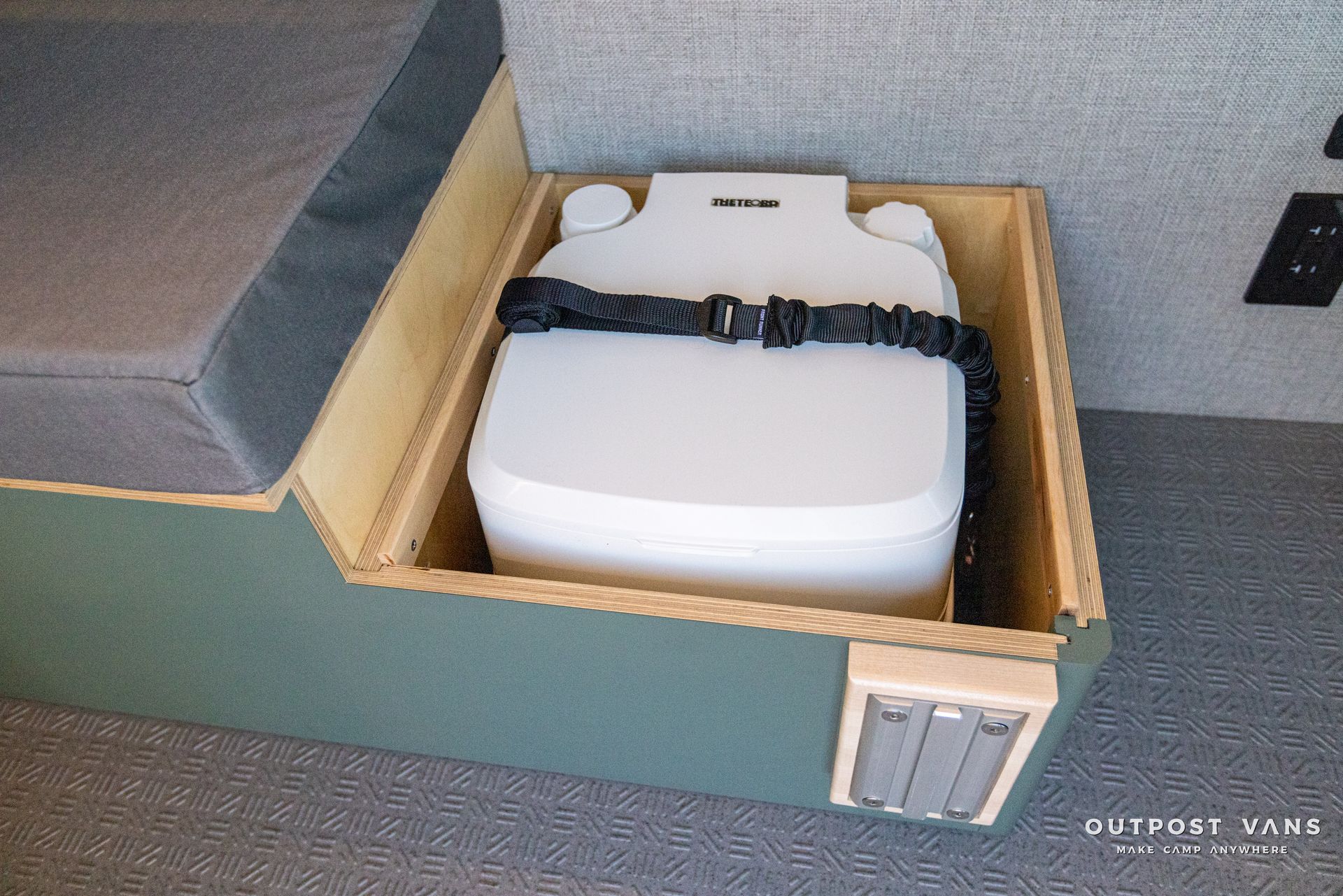 a toilet is sitting in a wooden box under a bed .