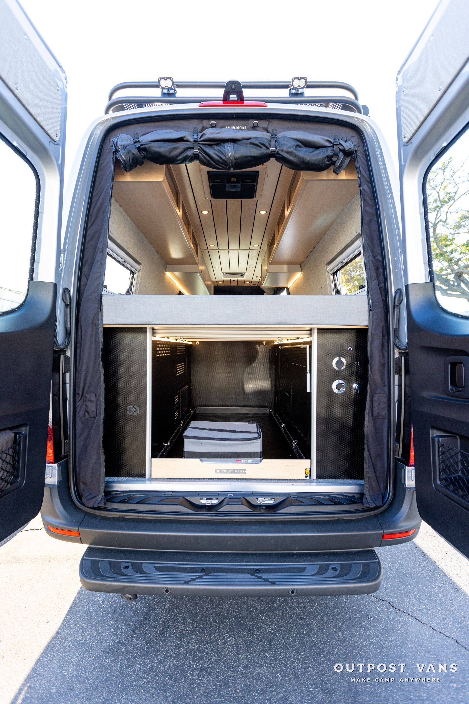 the back of a van with its doors open and a bed in the back .