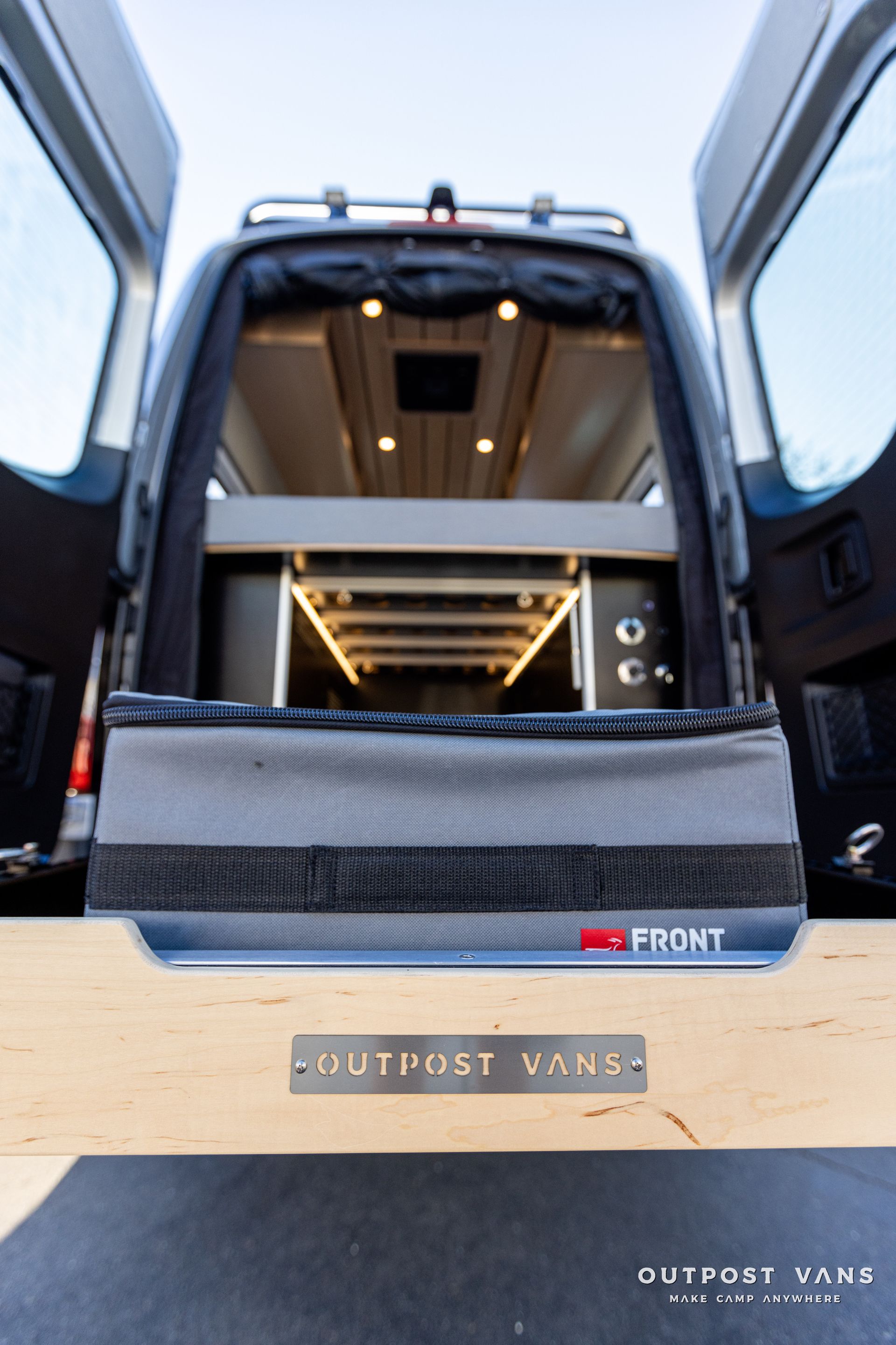 the back of a van with the doors open and a sign that says outpost vans