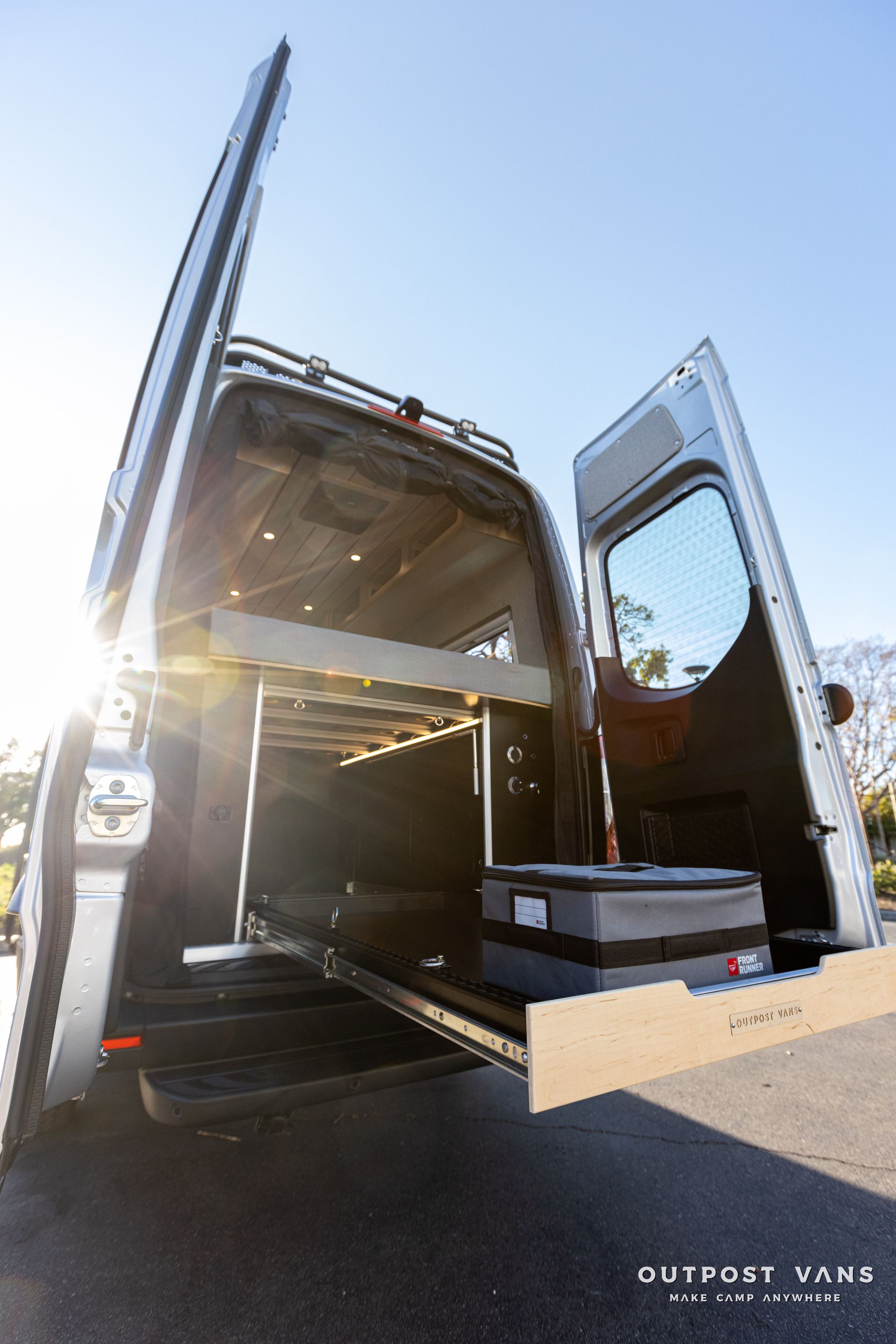 the back of a van with its doors open and a suitcase in the back .