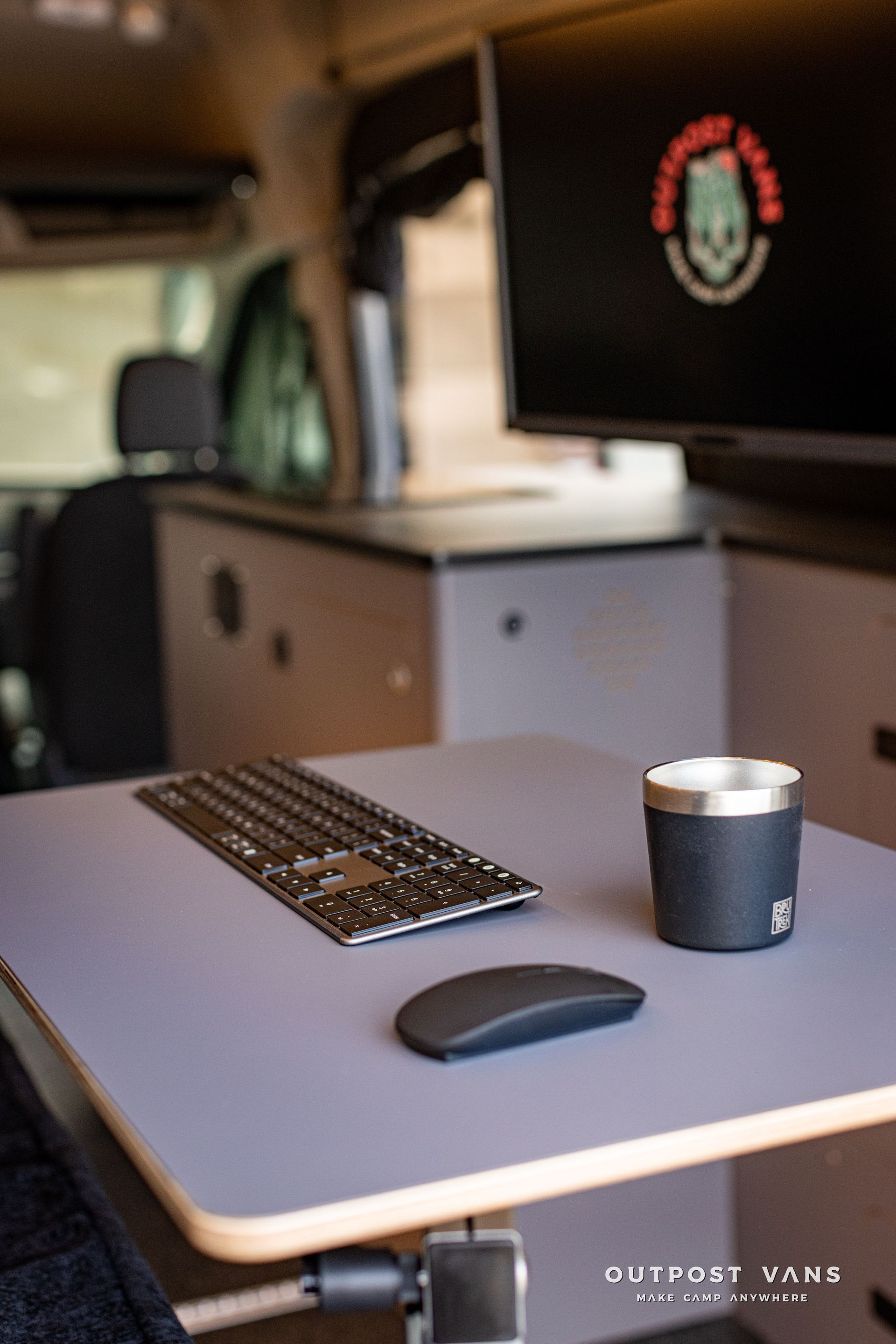 a desk with a keyboard , mouse , and cup on it .