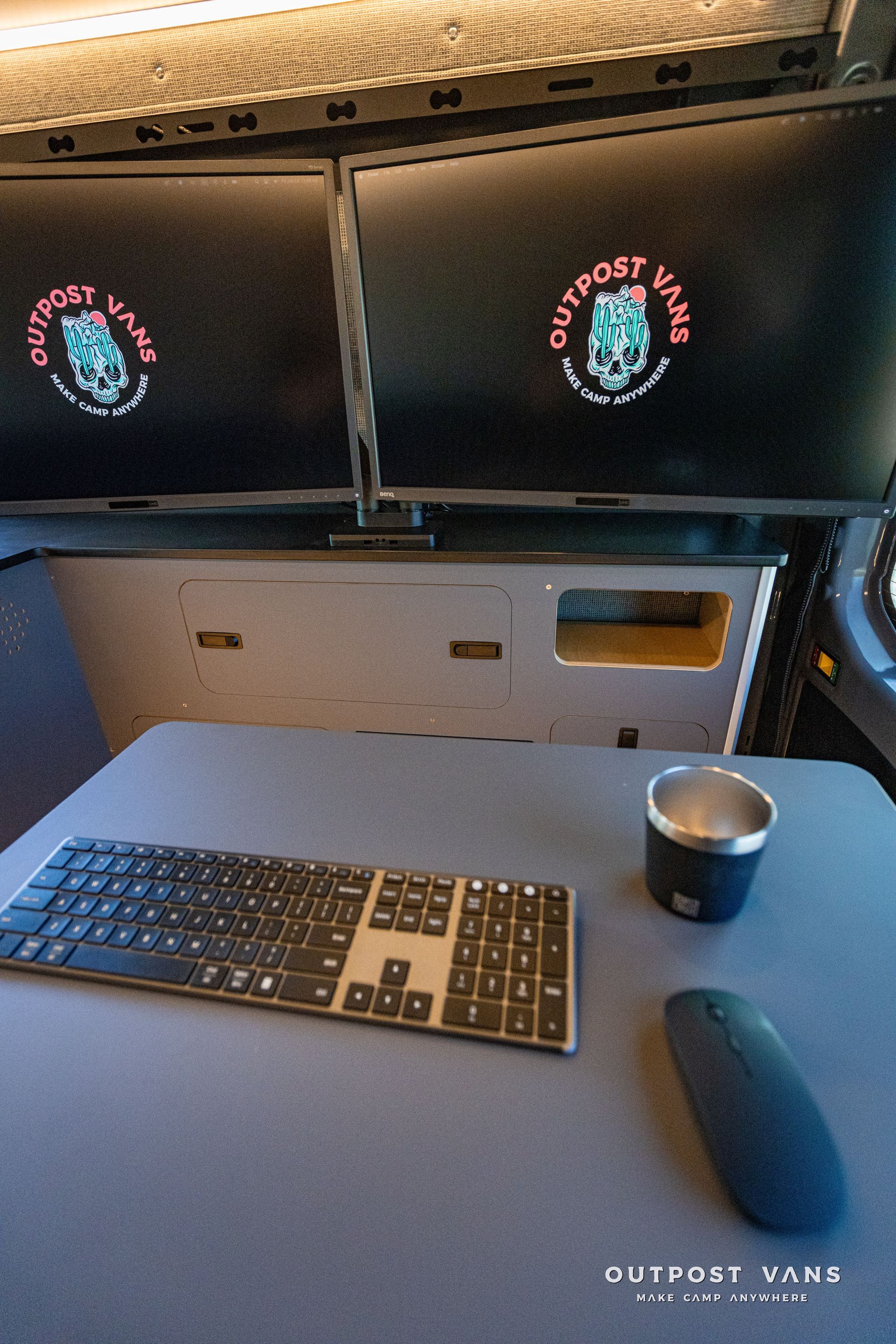 a desk with a keyboard a mouse and a cup on it