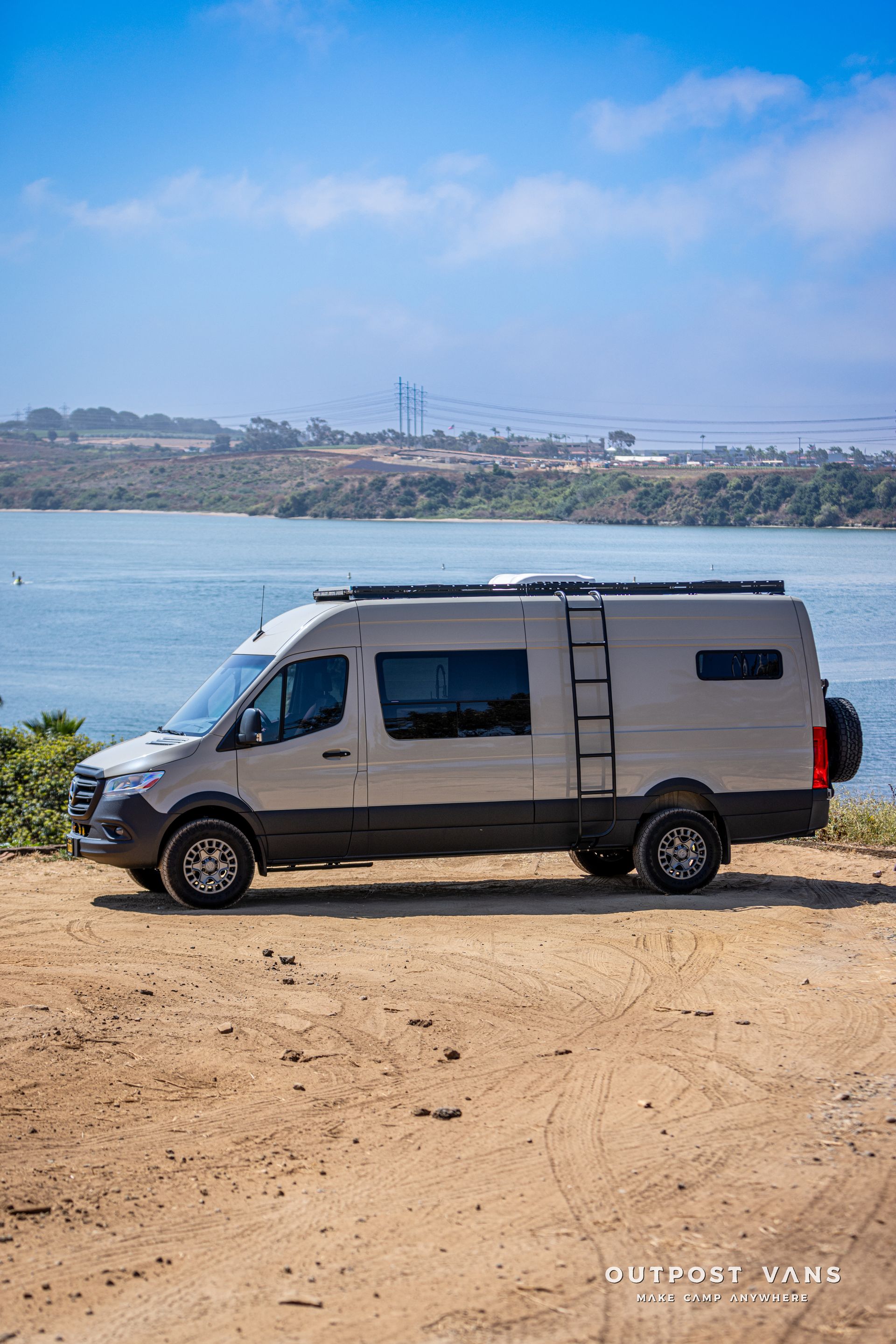 A van is parked on a dirt road next to a body of water.