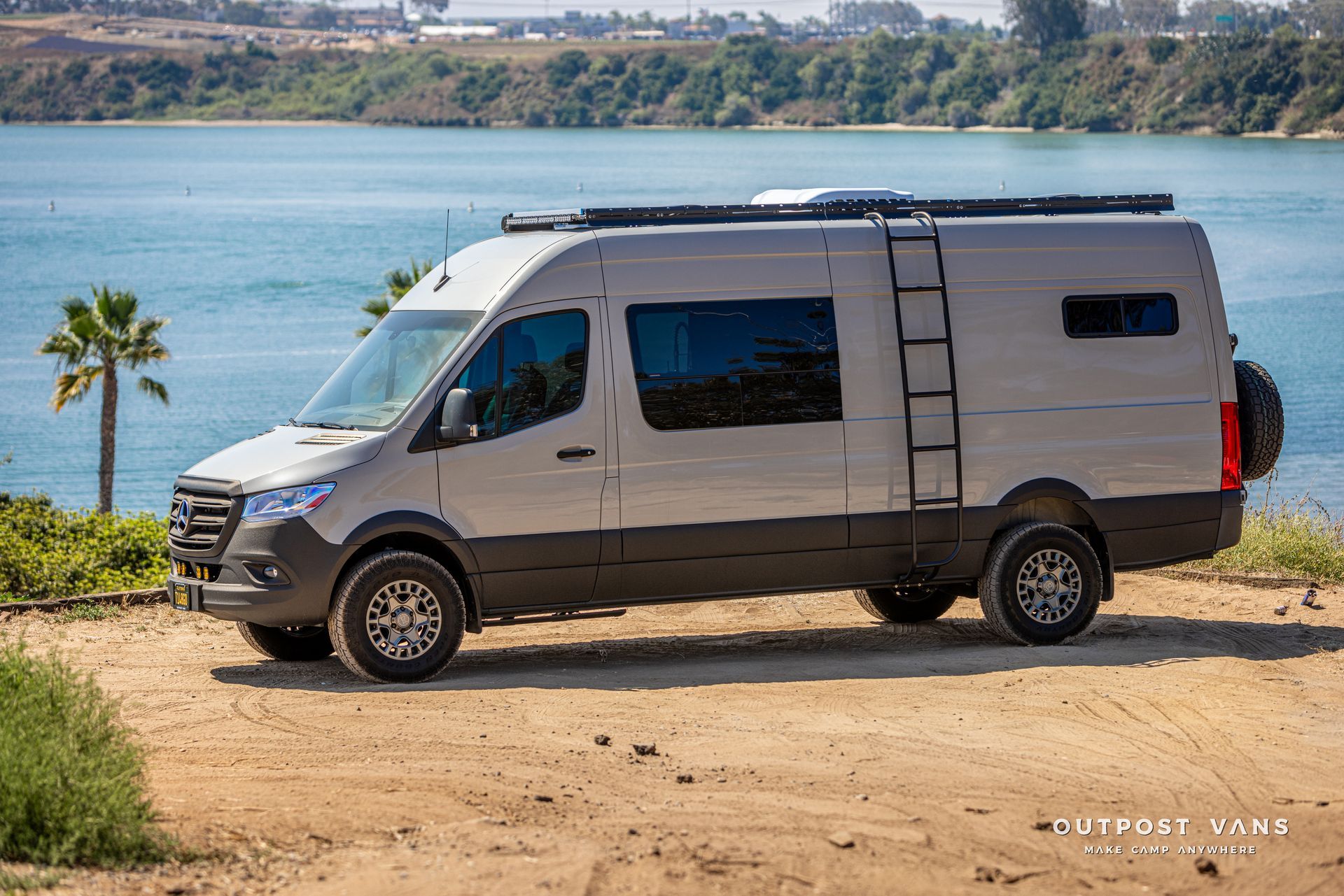 A van is parked on a dirt road next to a body of water.