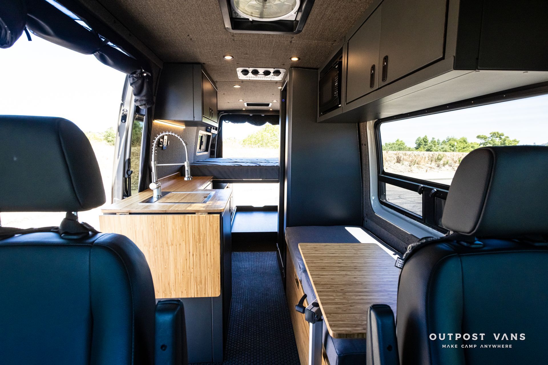 The inside of a van with a wooden table and cabinets.