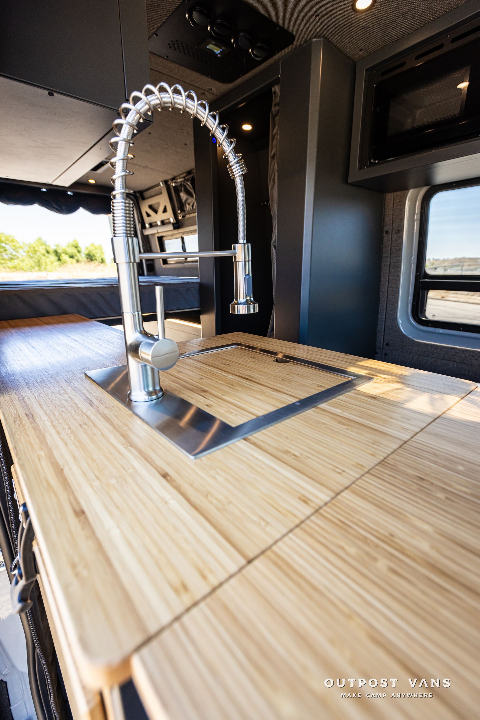 A kitchen sink with a faucet on a wooden counter top.