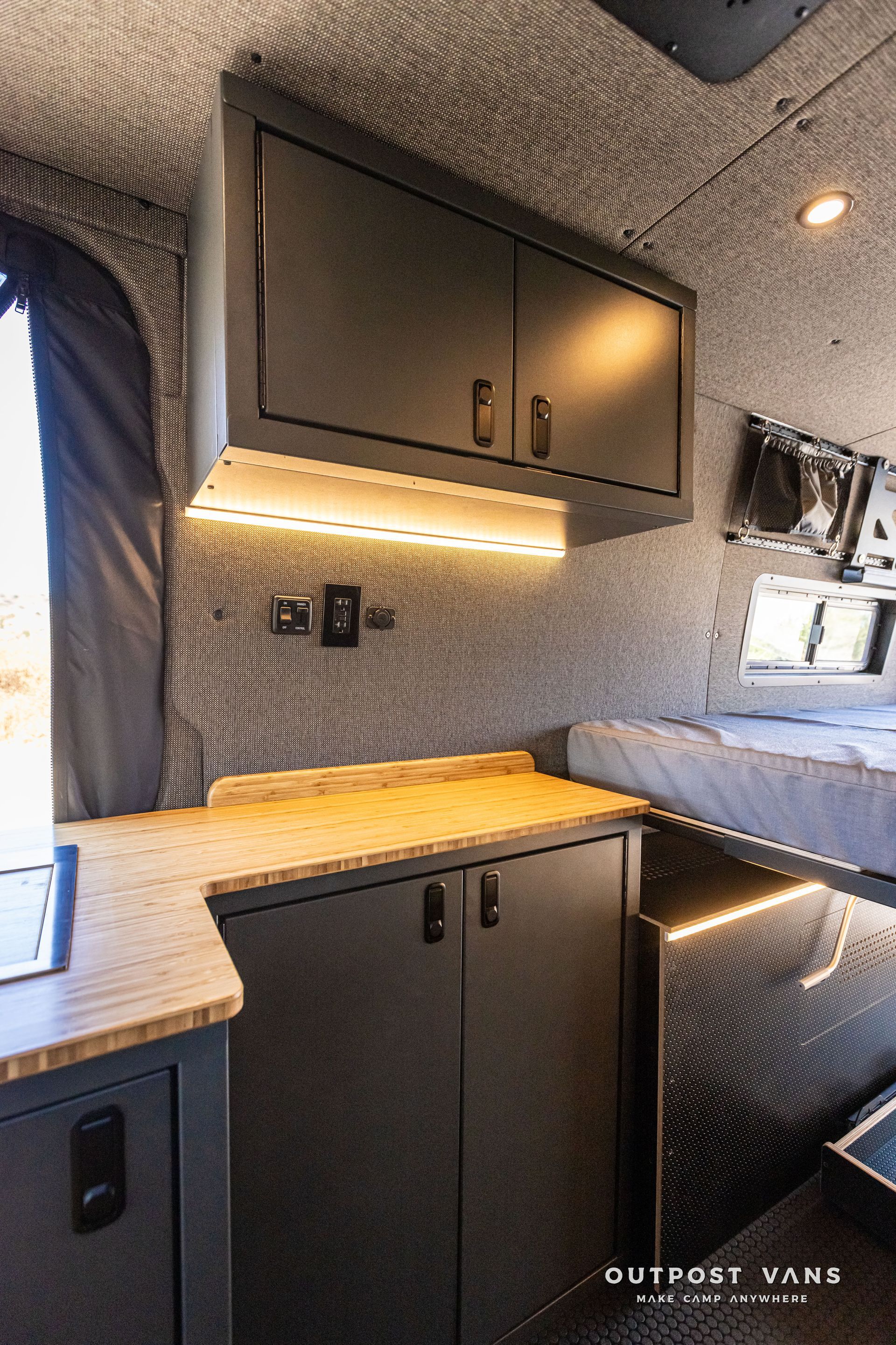 The inside of a camper van with a bed and cabinets.