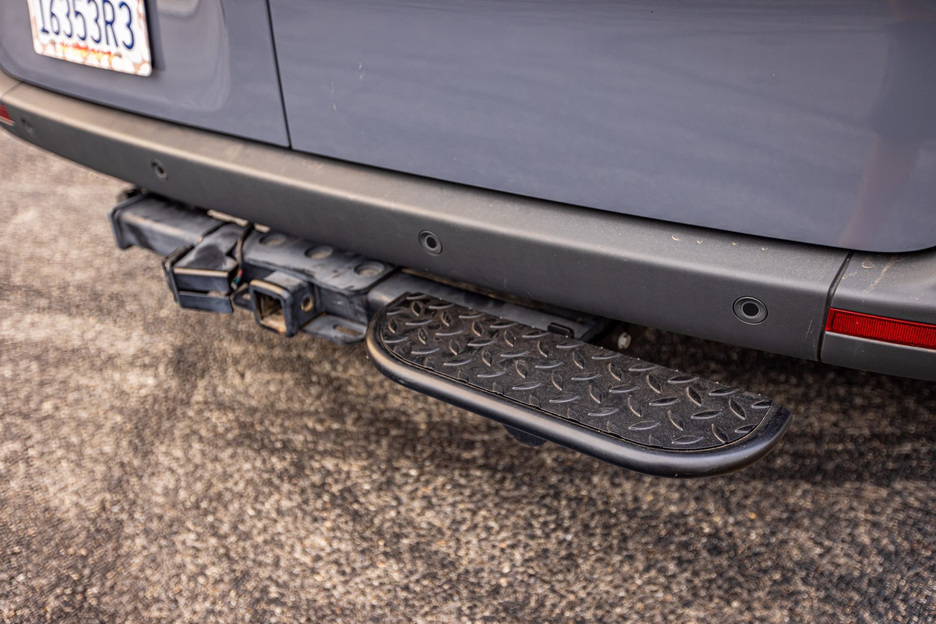 The rear bumper of a van with a step attached to it.