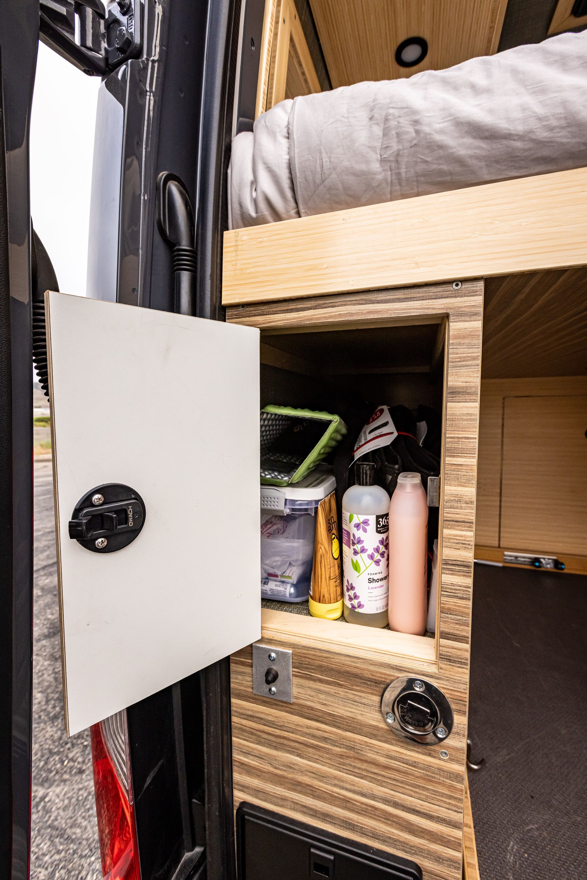 A van with the door open and a shelf with bottles in it.