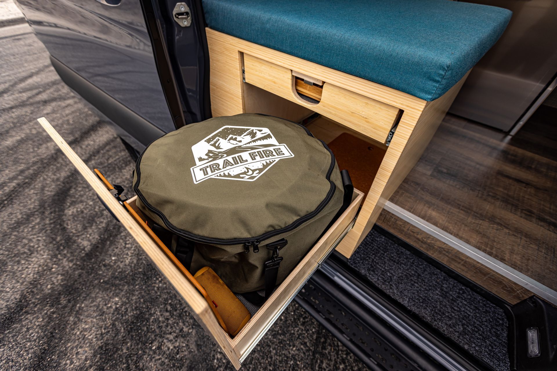 A green bag is sitting in a drawer in the back of a van.