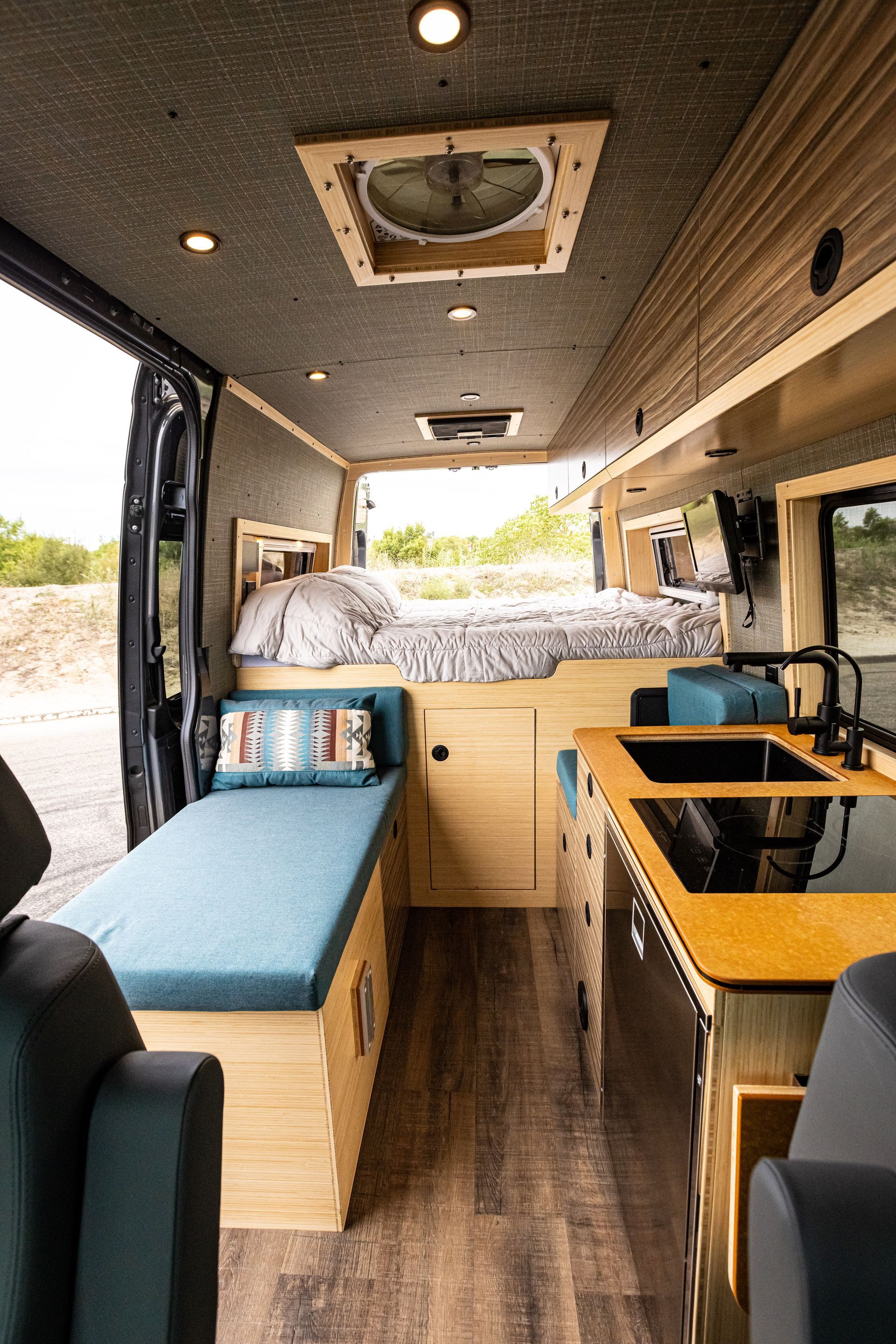 The inside of a van with a bed and a kitchen.