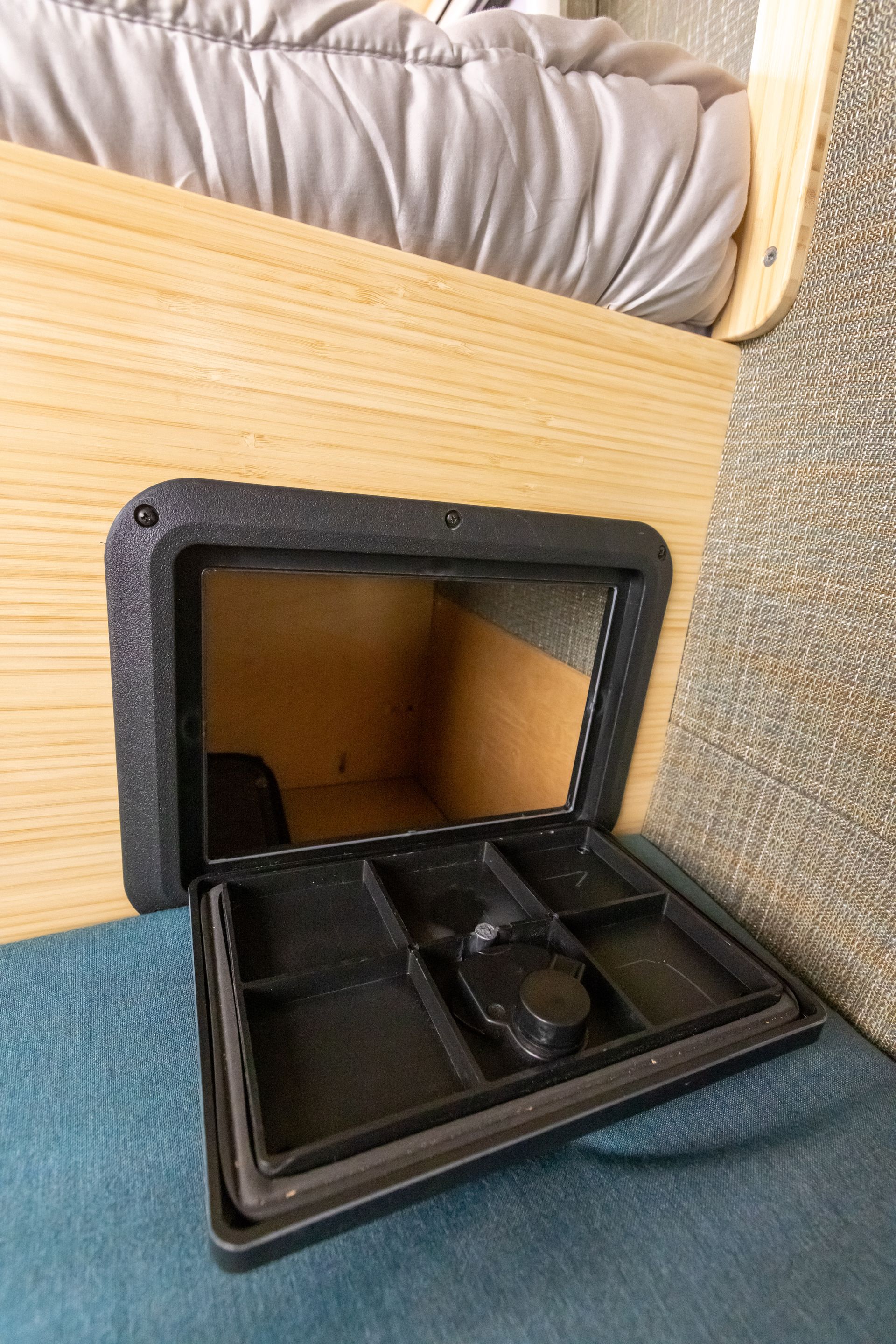 A small box with a mirror inside of it is sitting under a bed.