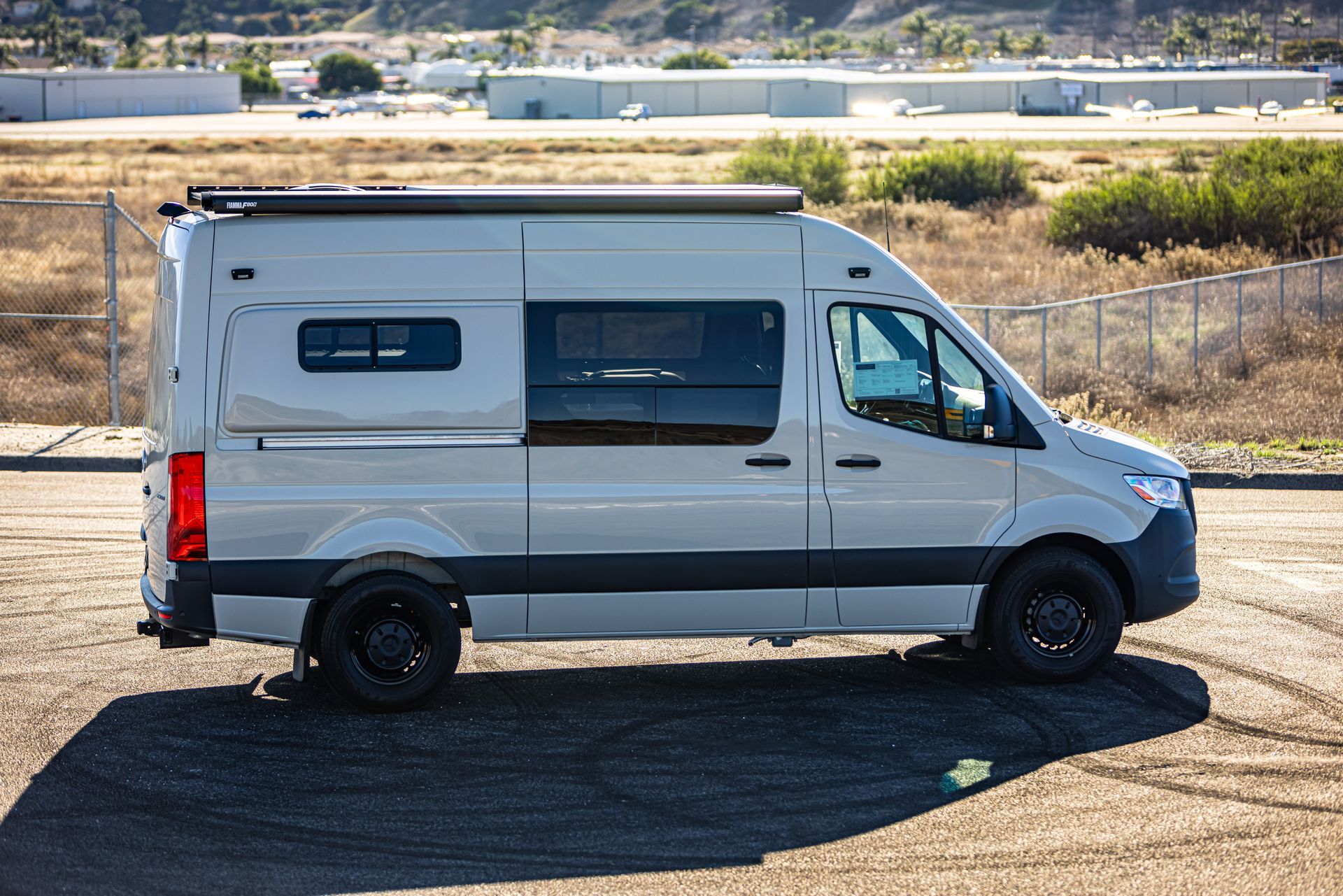 A white van is parked in a dirt lot.