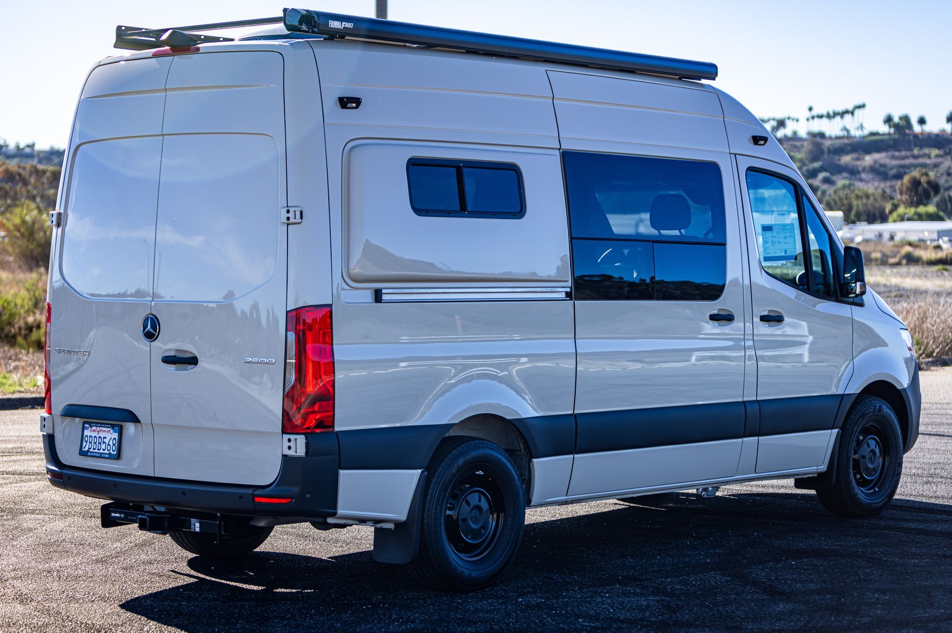 A white van is parked on a dirt road.