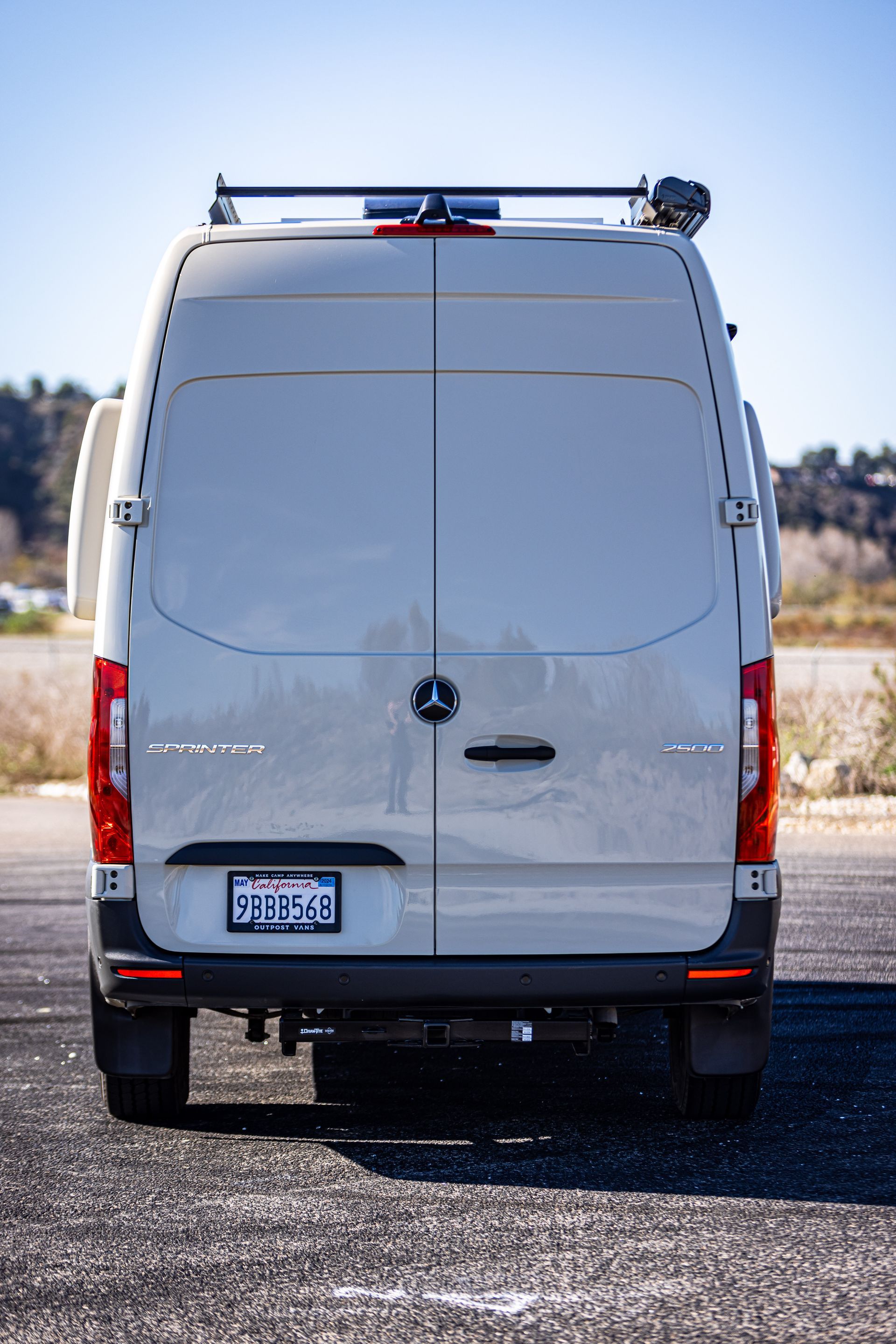 The back of a white van is parked on the side of the road.