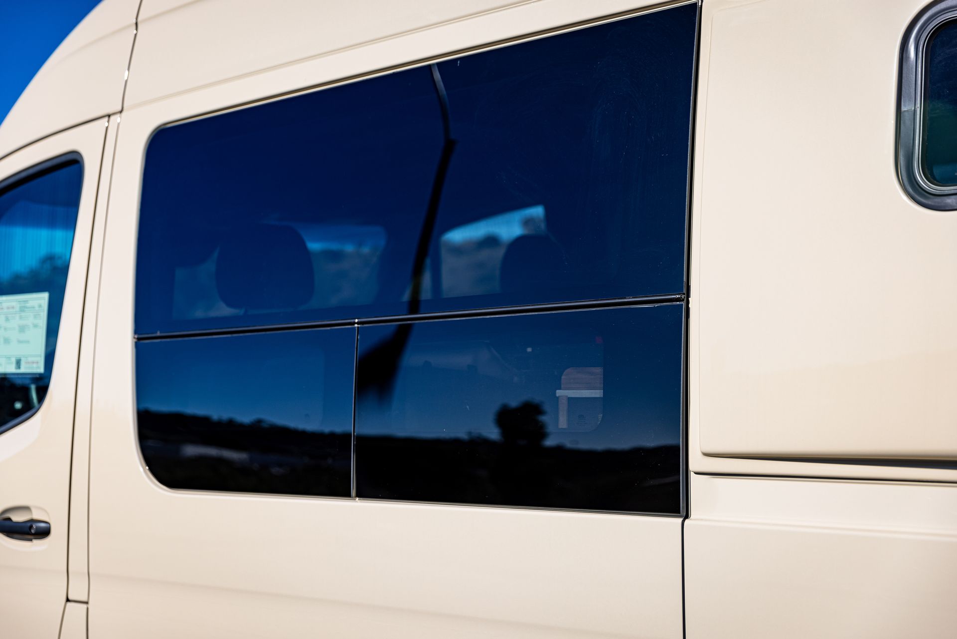 A white van with a lot of windows and a blue sky in the background