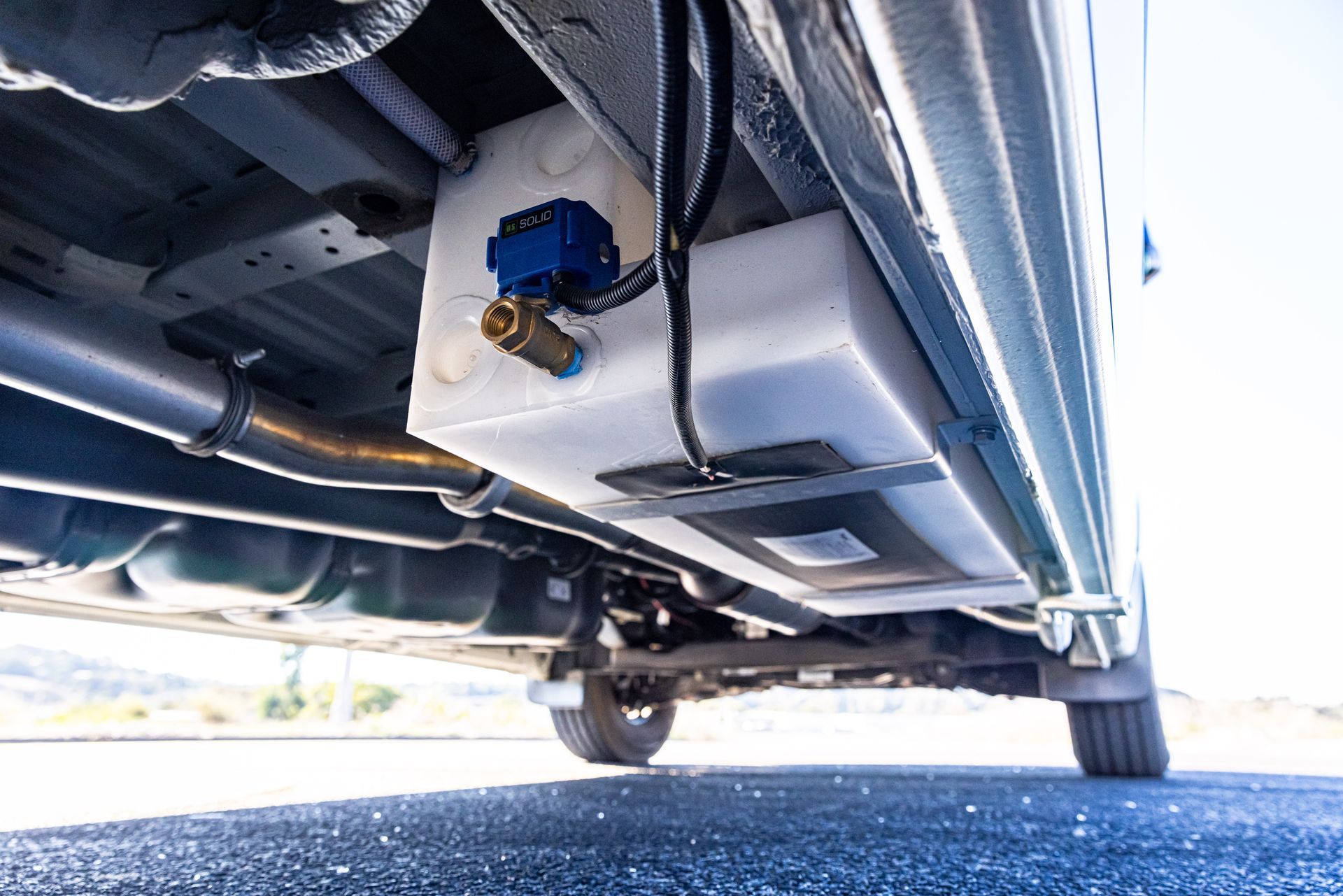 The underside of a car with a water tank attached to it.